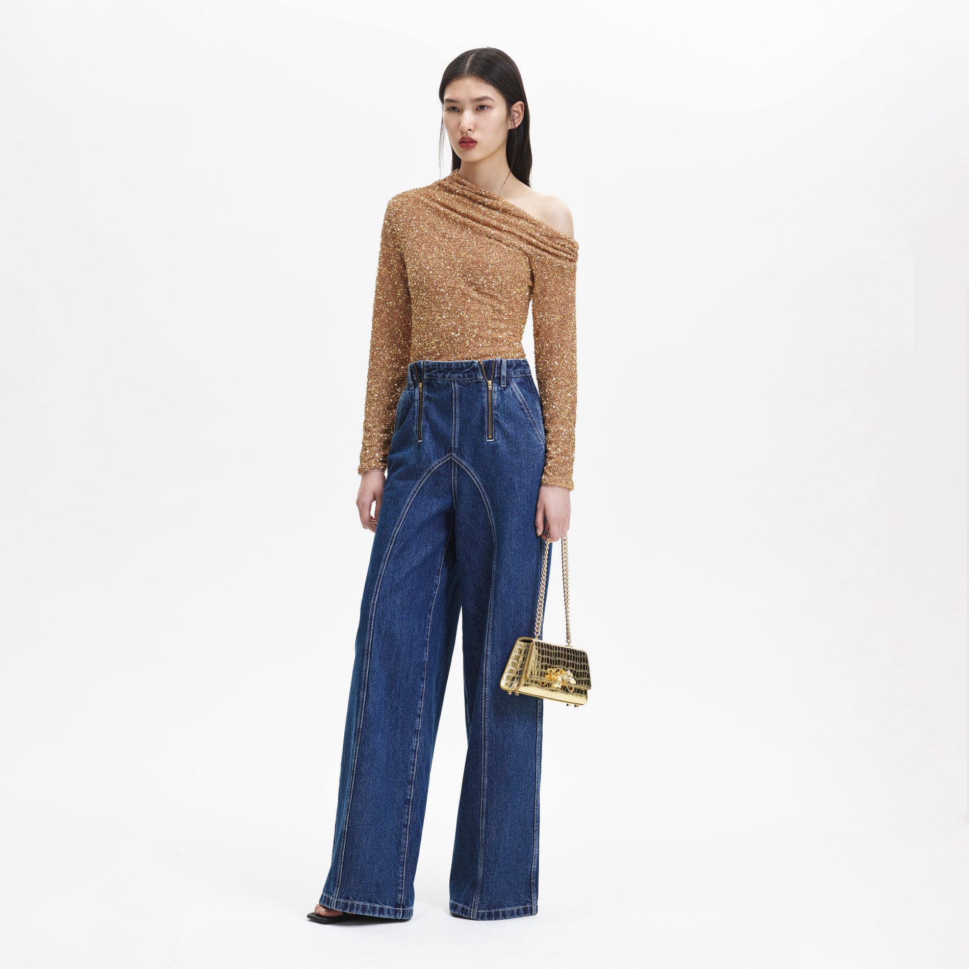 Side view of a woman wearing the Gold Sequin Asymmetric Top