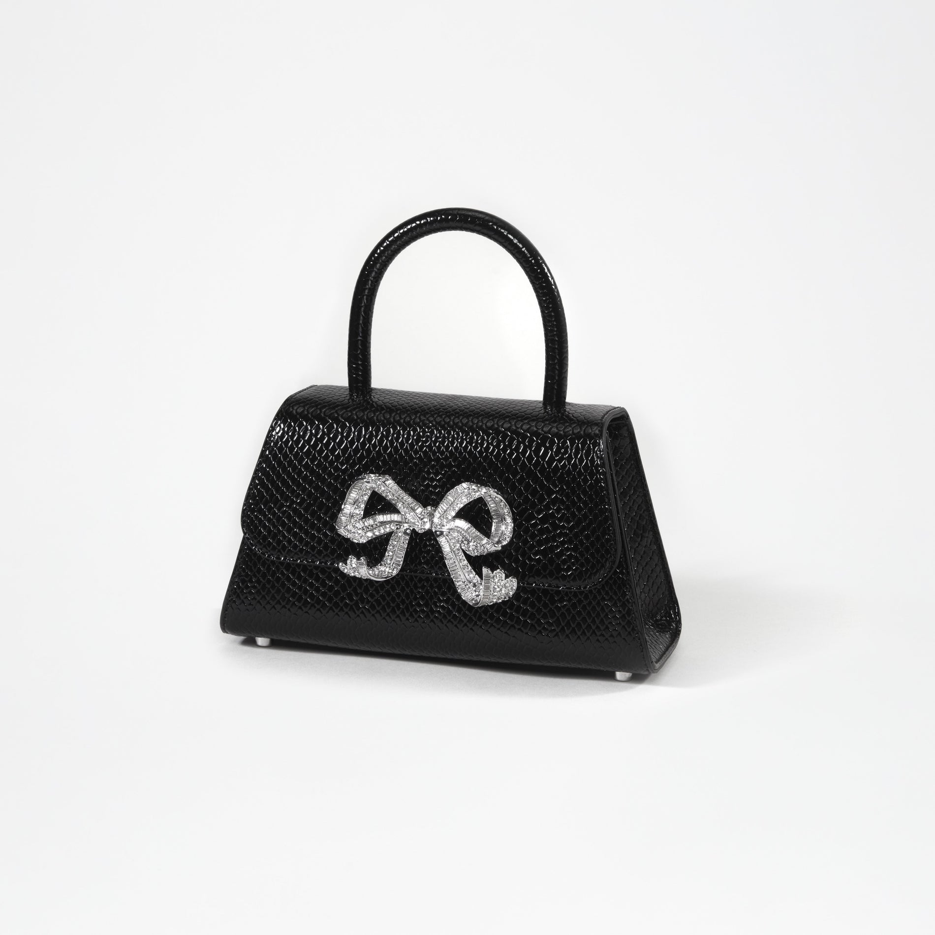 A woman wearing the Black Python Diamante Bow Mini Bag