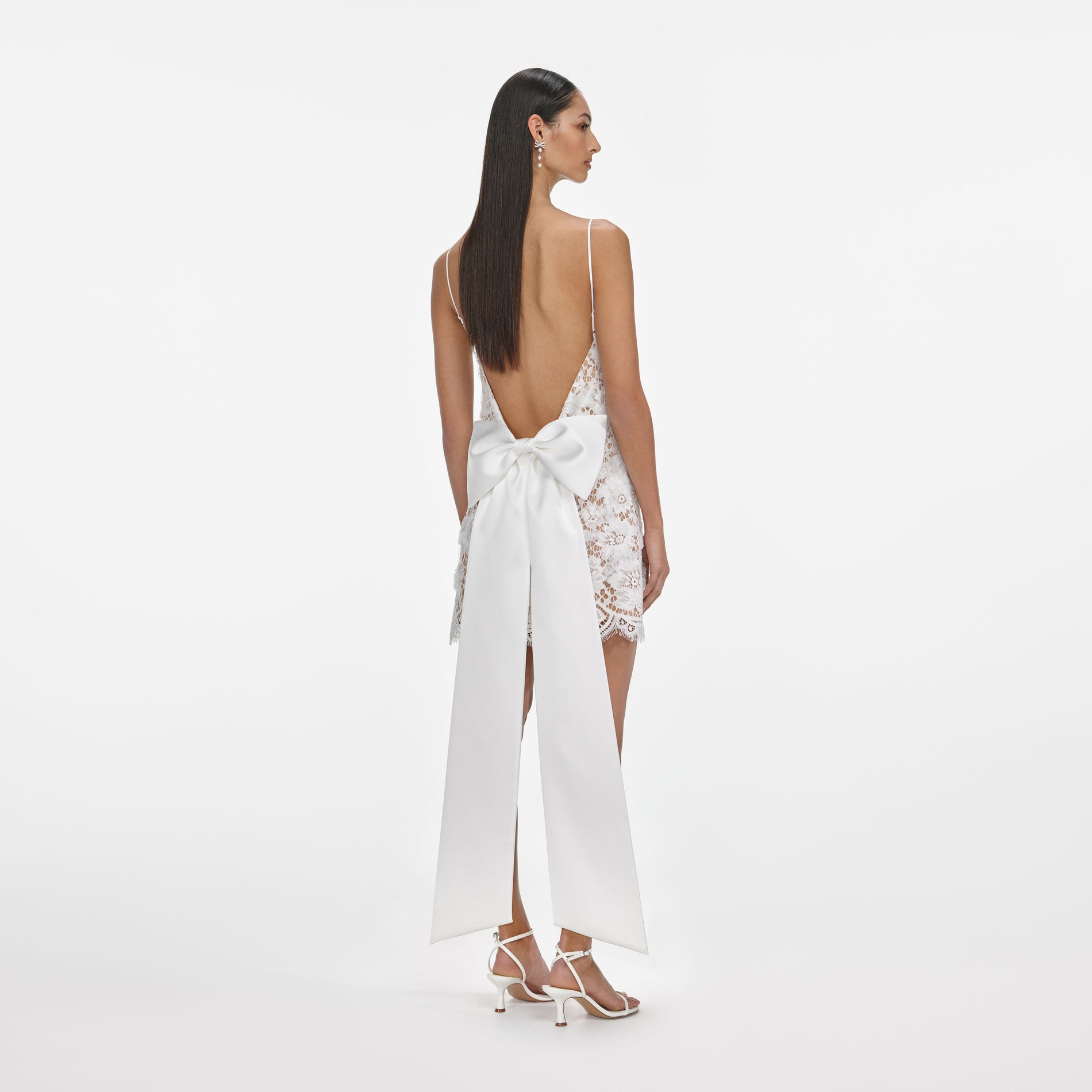 Back view of a woman wearing the White Lace Satin Bow Mini Dress