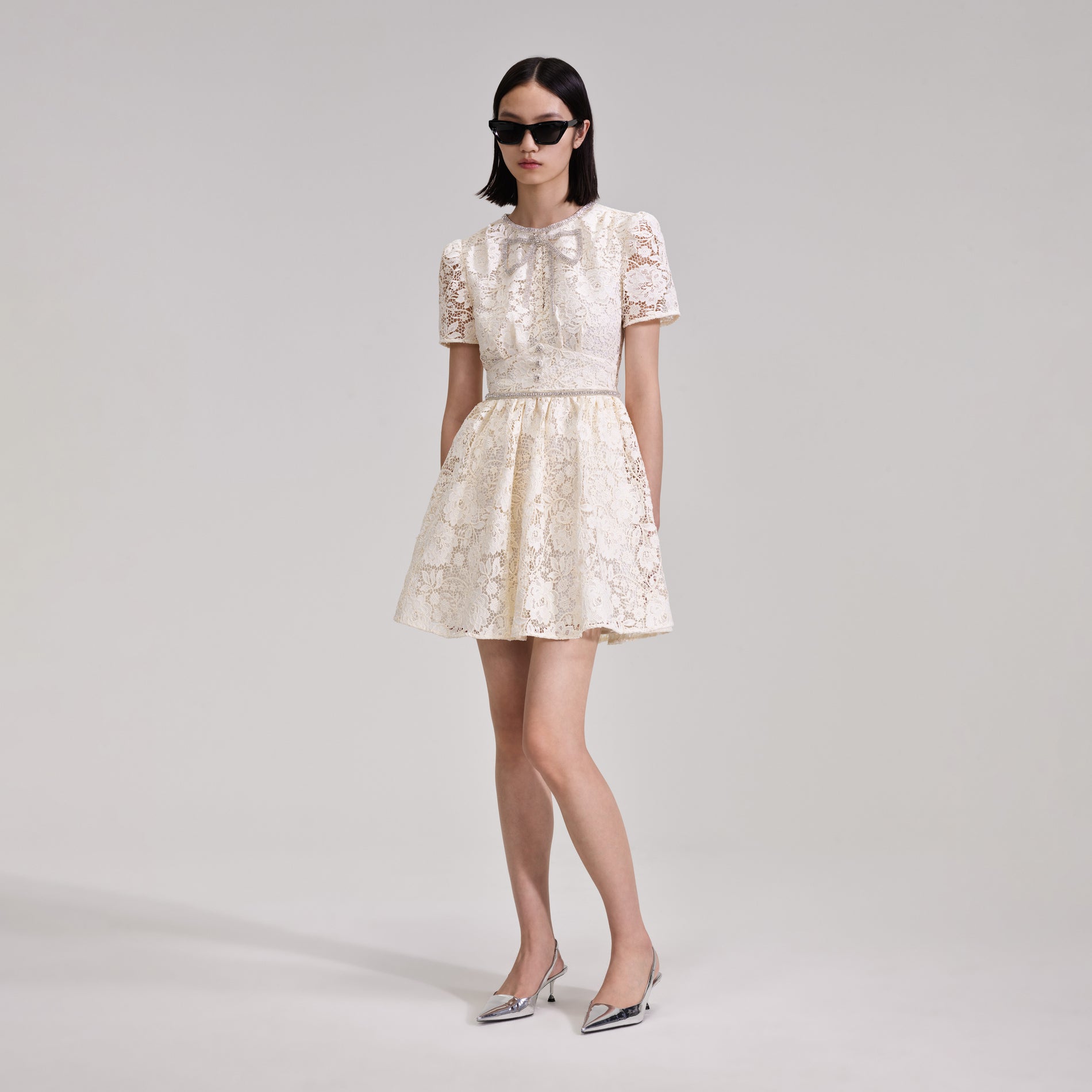 A woman wearing the Cream Cord Lace Bow Mini Dress