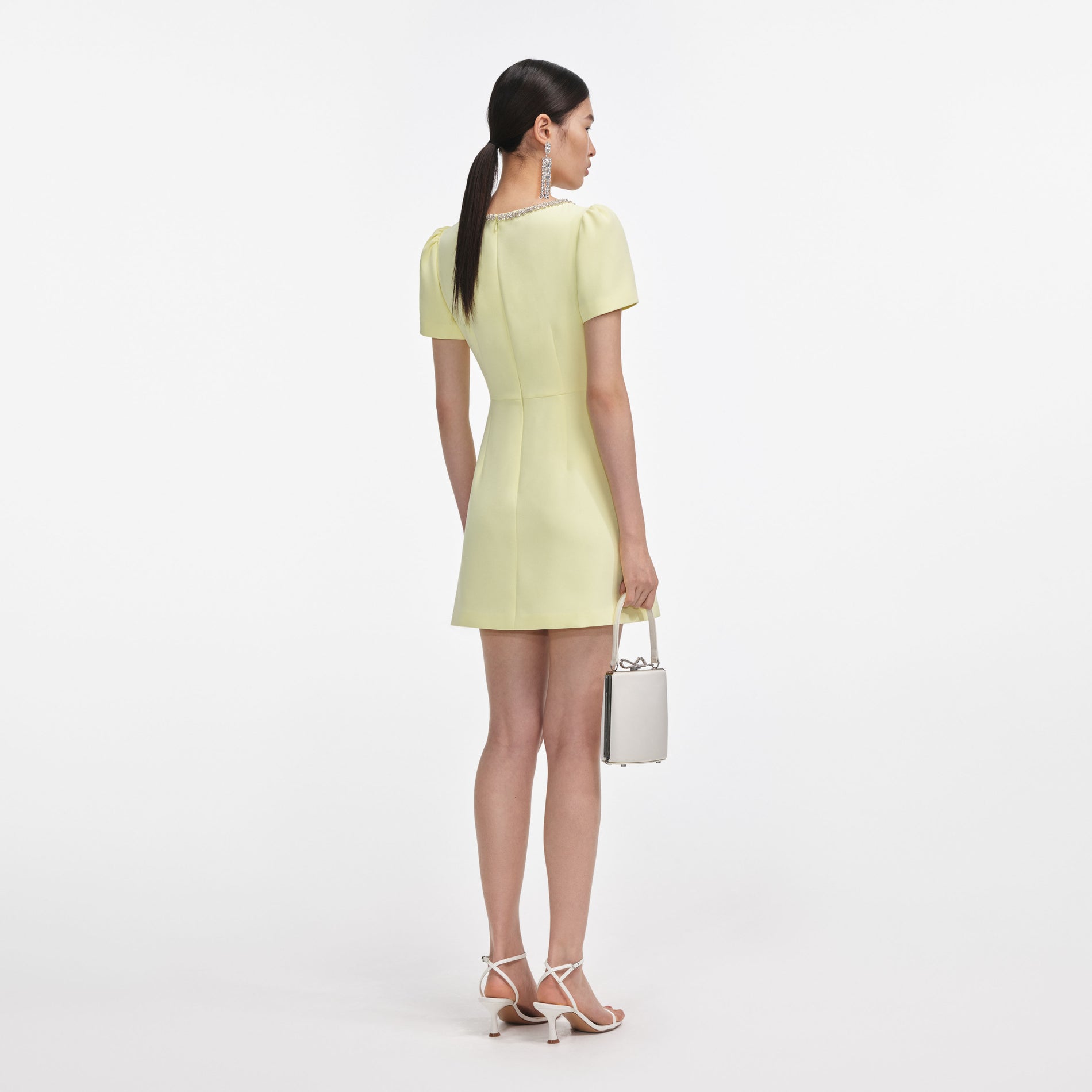 Back view of a woman wearing the Yellow Crepe Crystal Trim Mini Dress