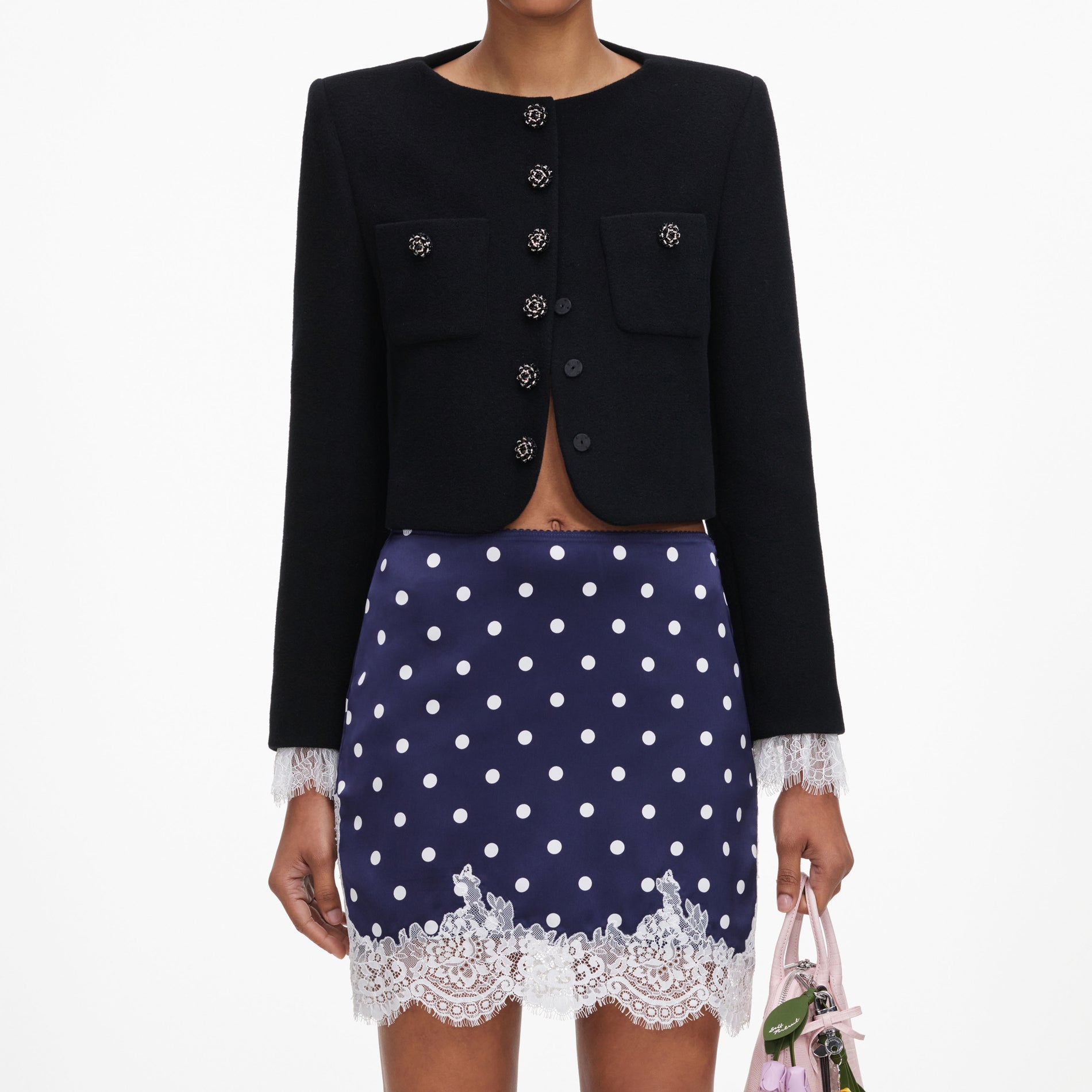 A close up of a woman wearing the Navy Polka Dot Satin Mini Skirt