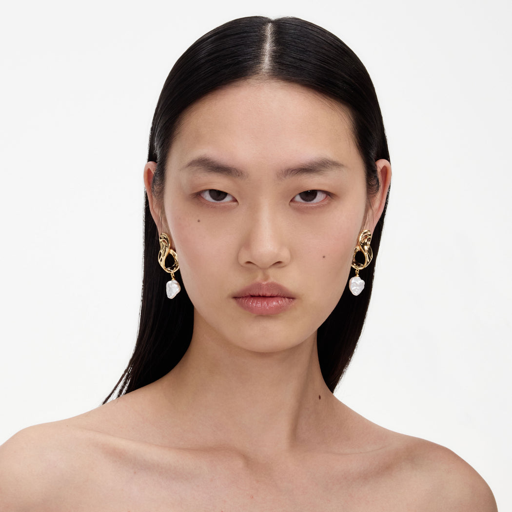 A close up of a woman wearing the Gold Link Pearl Drop Earrings