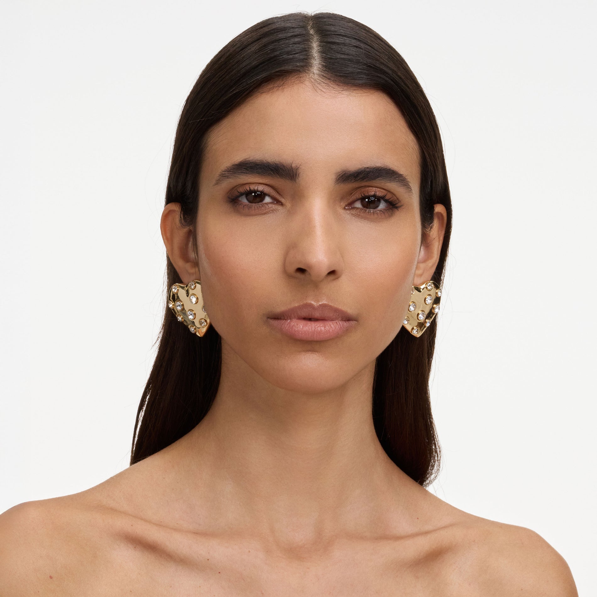 A close up of a woman wearing the Gold Crystal Heart Earrings