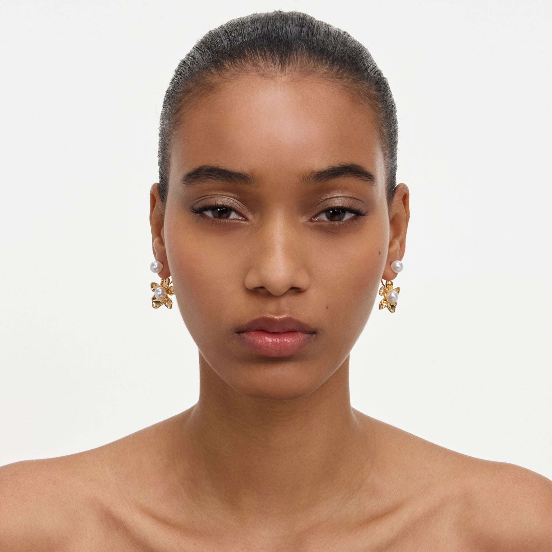 A close up of a woman wearing the Gold Flower Pearl Jacket Earrings