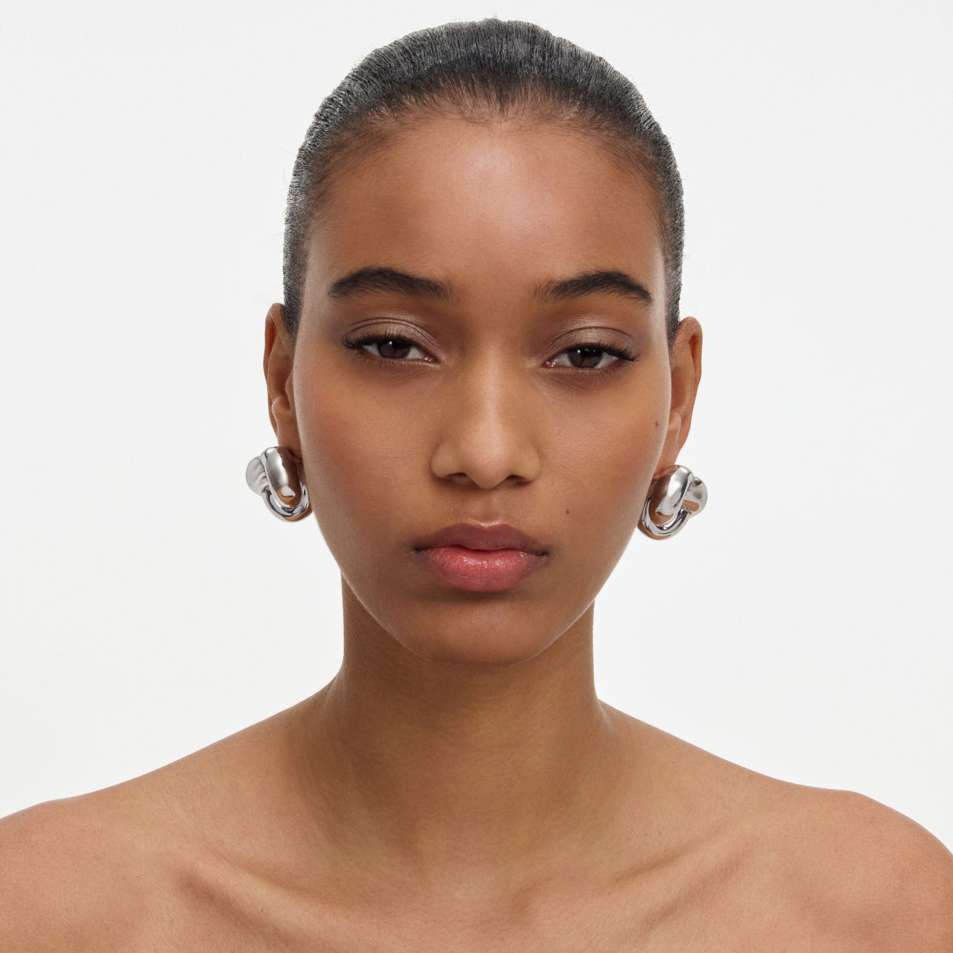 A close up of a woman wearing the Silver Knot Earrings