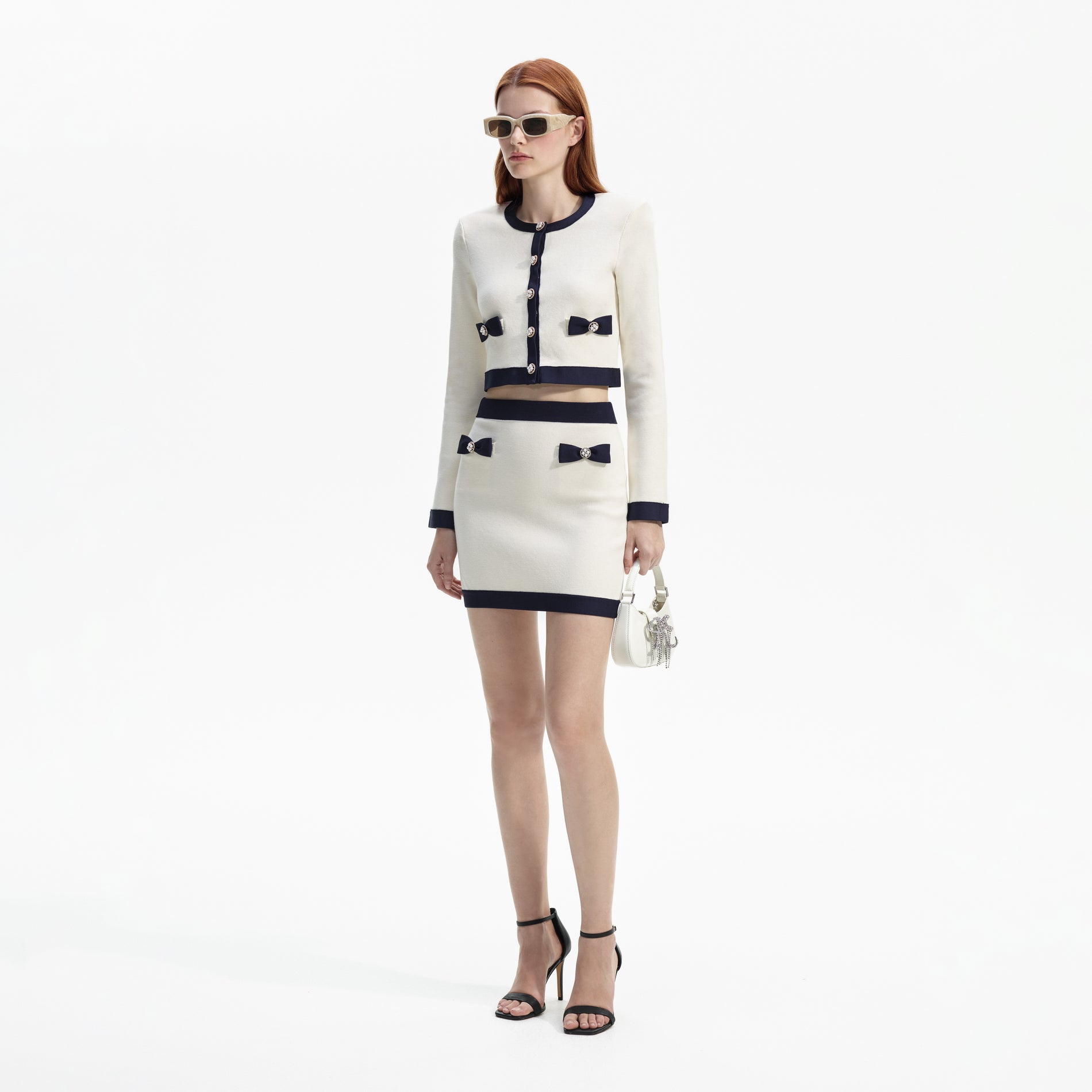 Side view of a woman wearing the Cream Knit Bow Mini Skirt