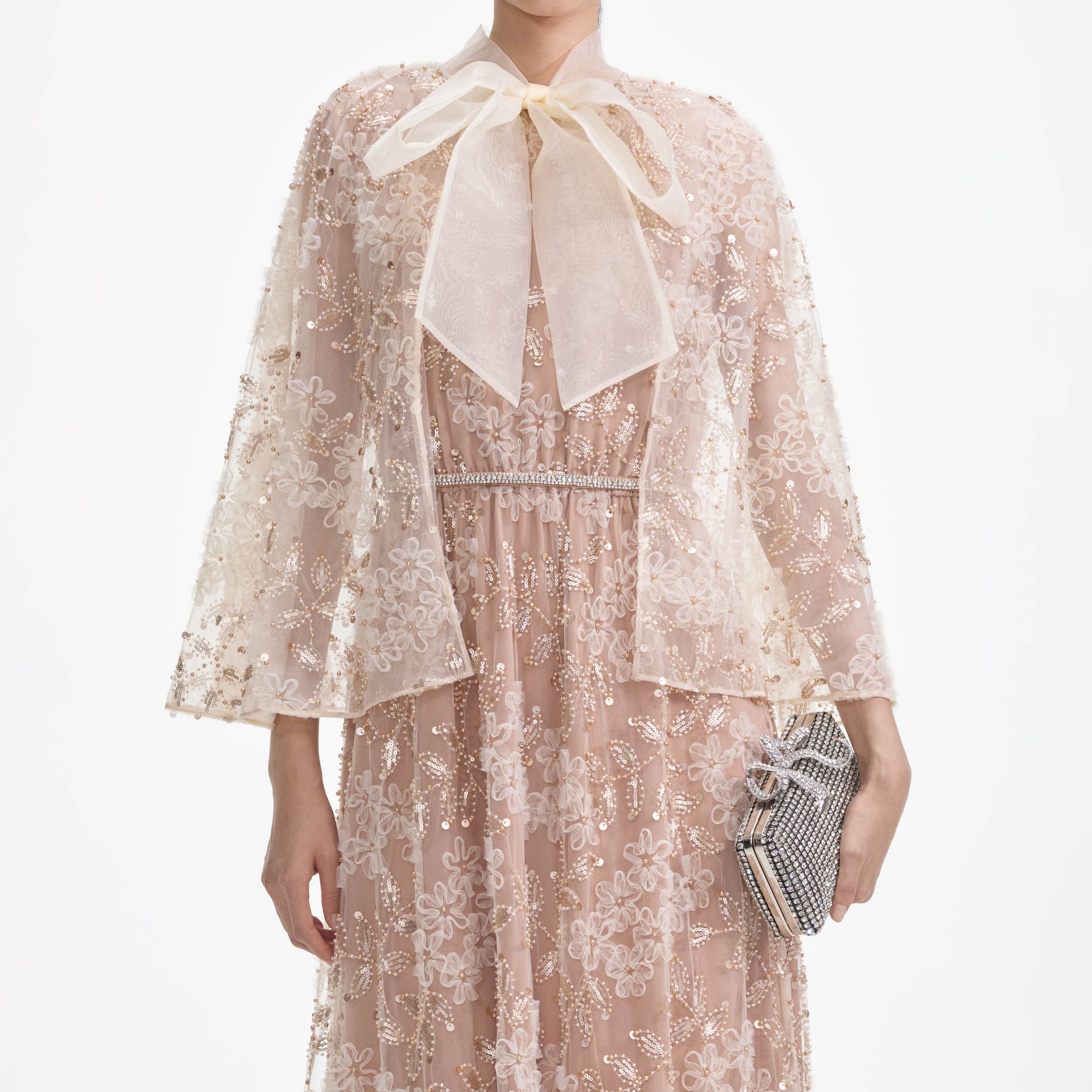 A close up of a woman wearing the Embellished Cape Maxi Dress