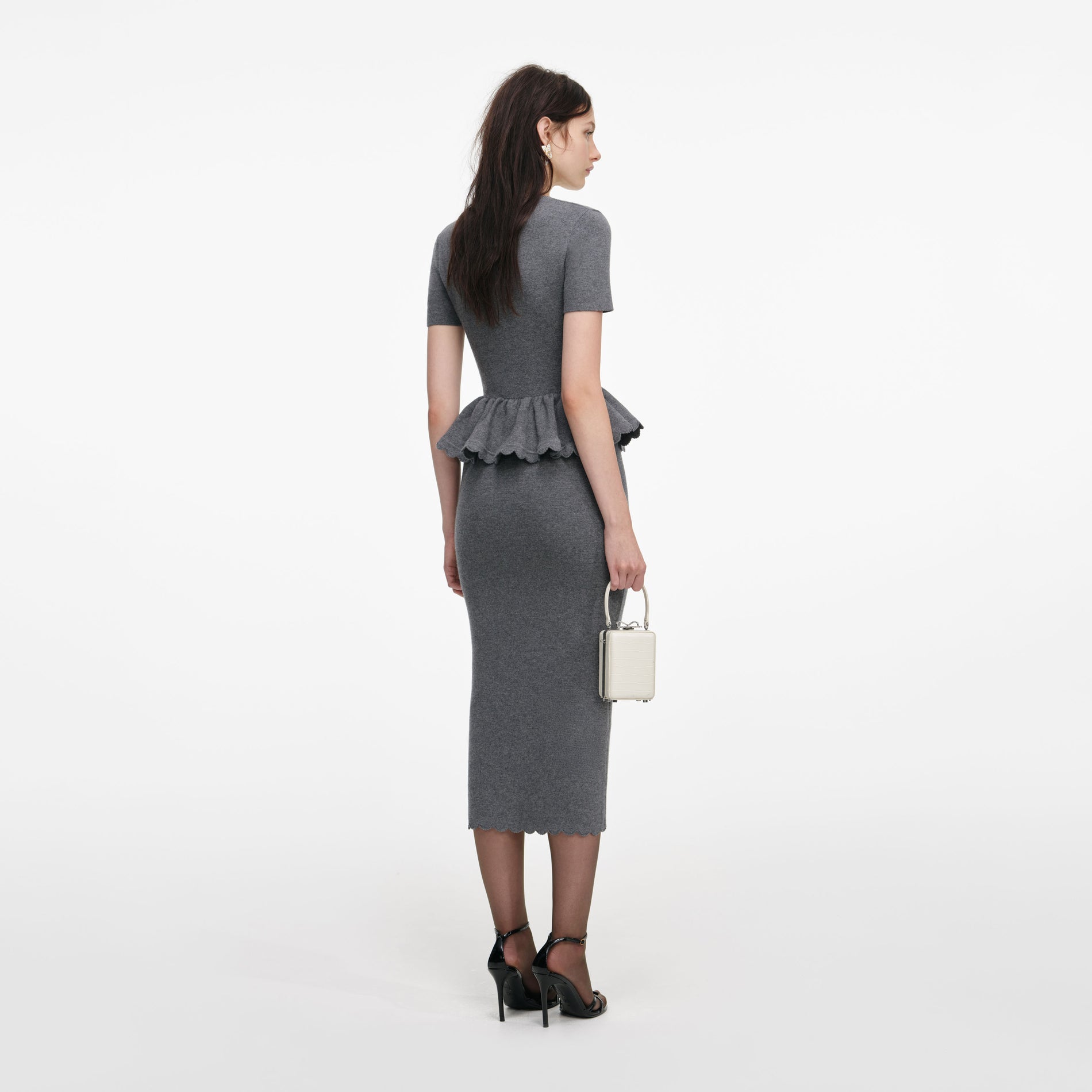Back view of a woman wearing the Grey Peplum Knit Midi Dress