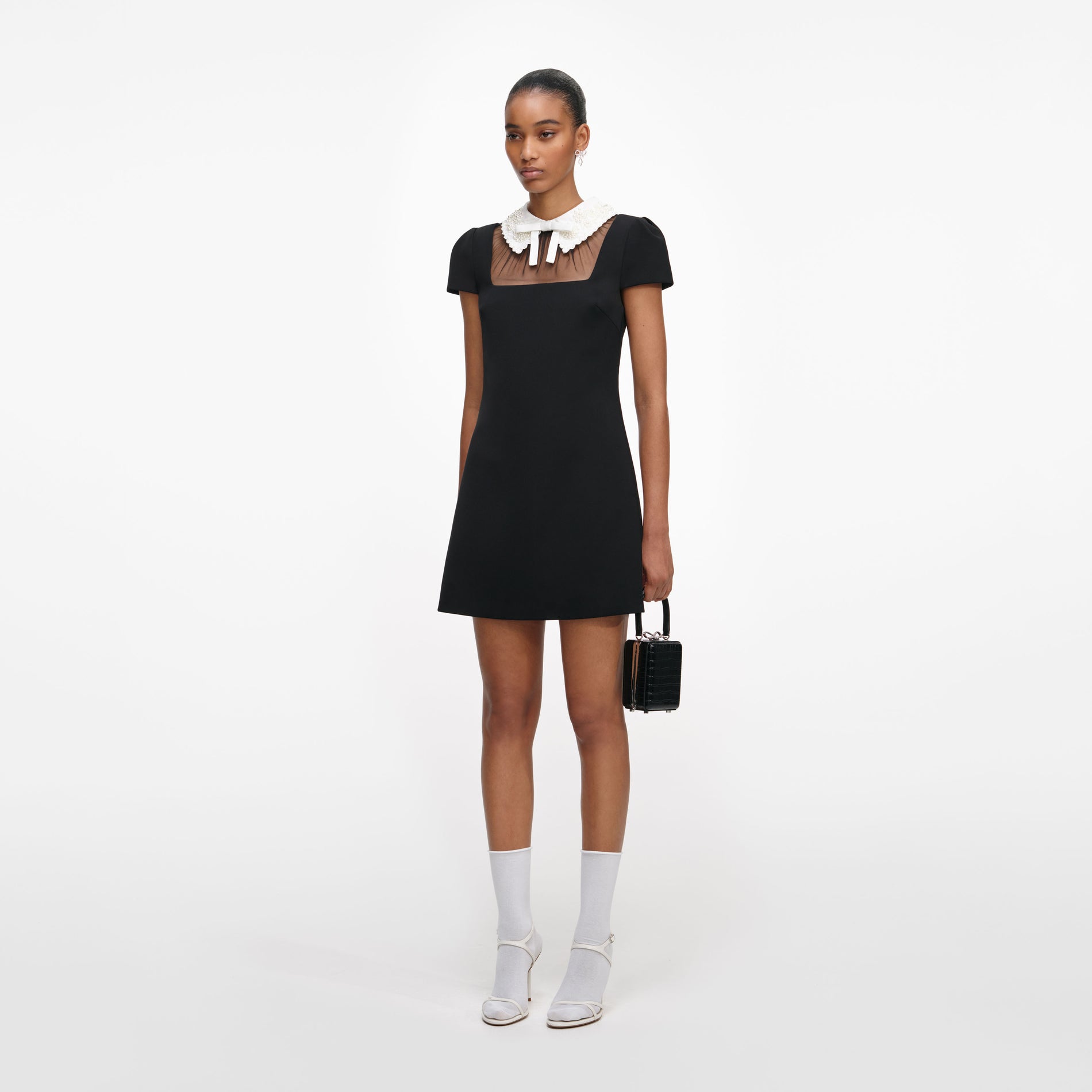 Side view of a woman wearing the Black Crepe Bow Collar Mini Dress