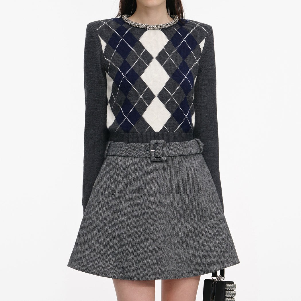 A close up of a woman wearing the Grey Argyle Crystal Trim Jumper