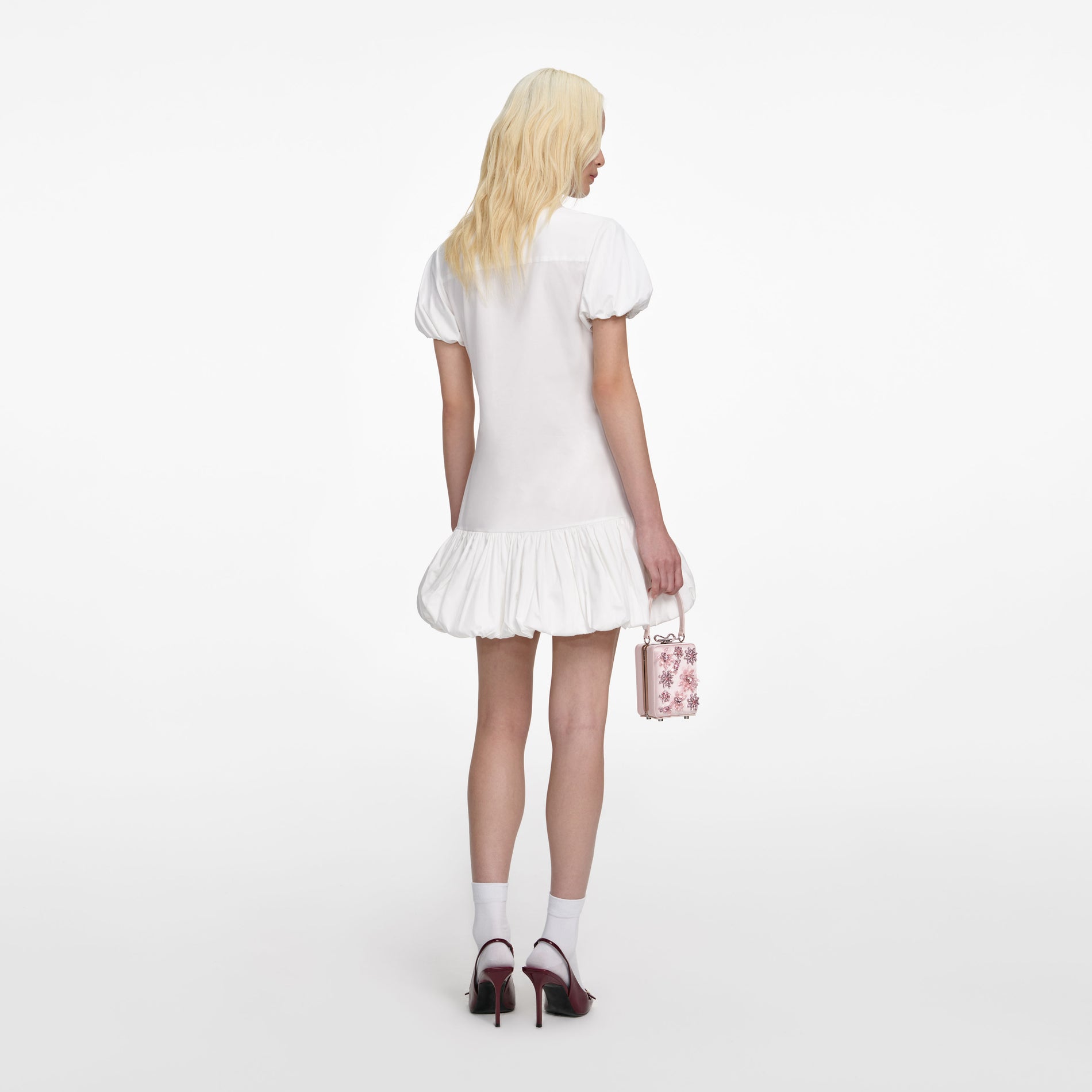 Back view of a woman wearing the White Cotton Asymmetric Mini Dress