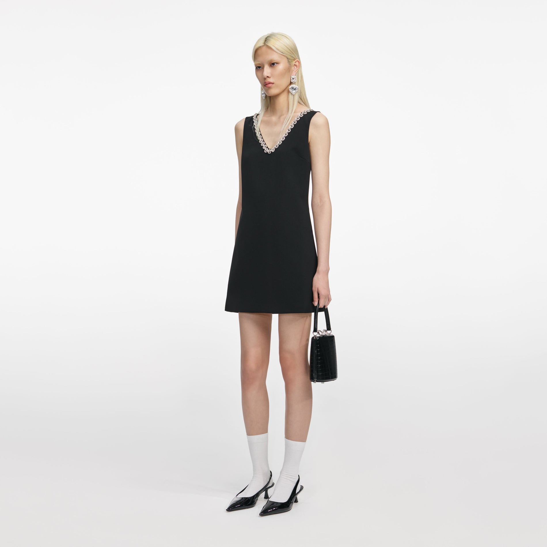 Side view of a woman wearing the Black Crepe Crystal Trim Mini Dress