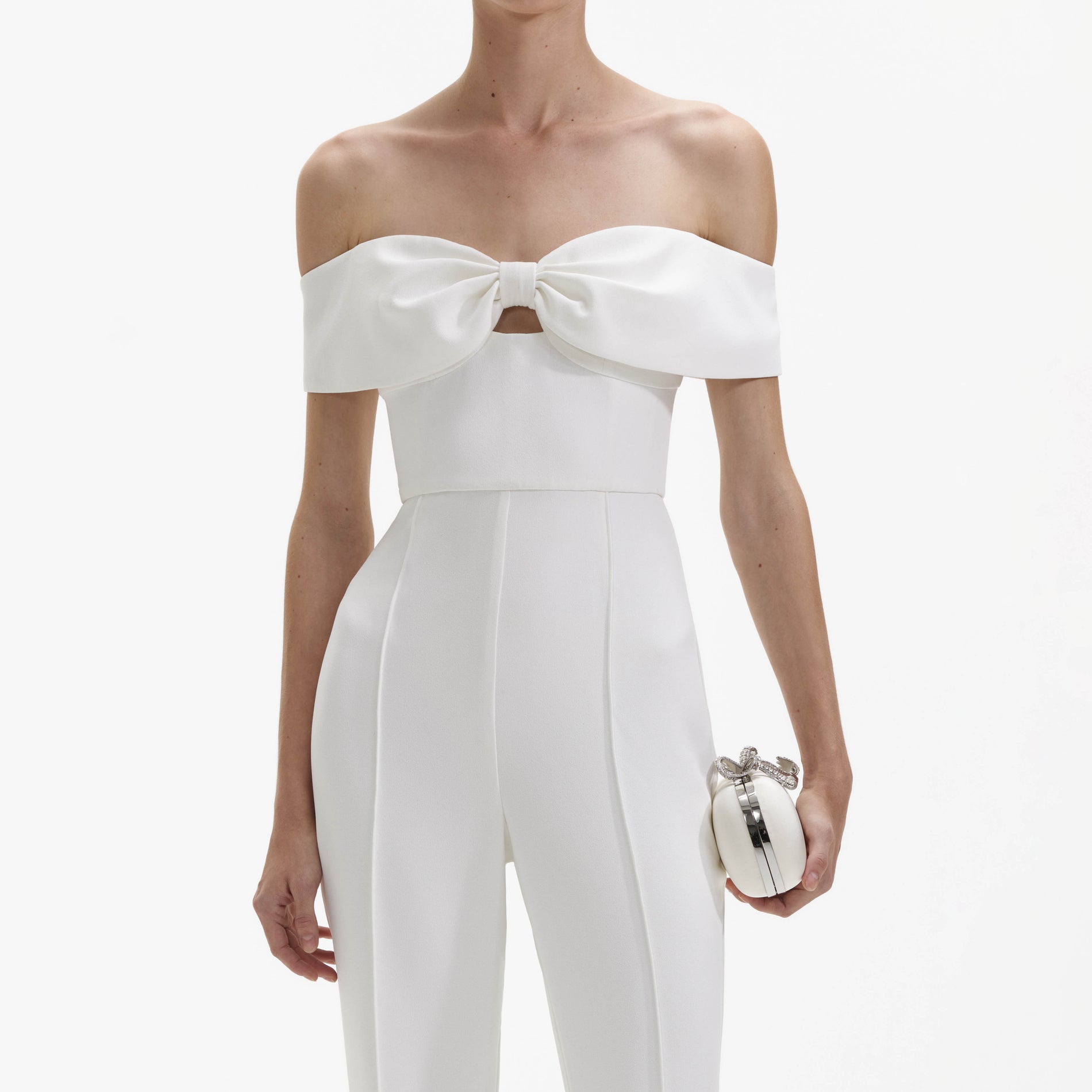 A close up of a woman wearing the White Crepe Bow Jumpsuit