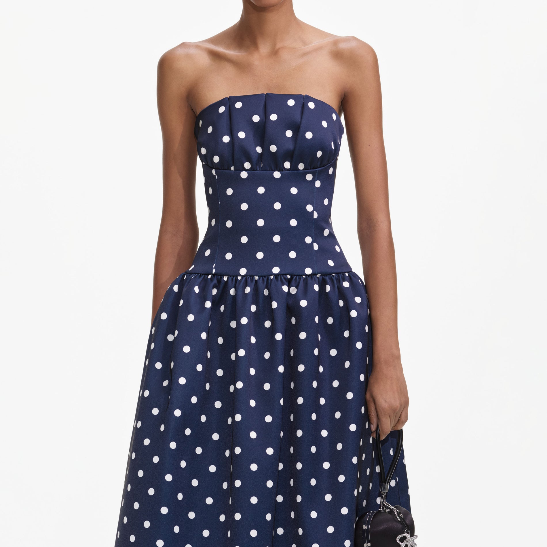 A close up of a woman wearing the Navy Polka Dot Satin Midi Dress
