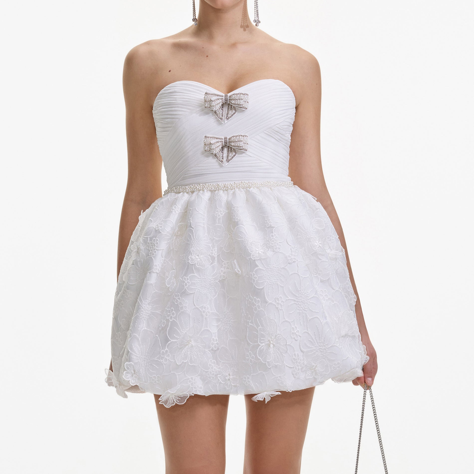 A close up of a woman wearing the White Organza Bow Mini Dress