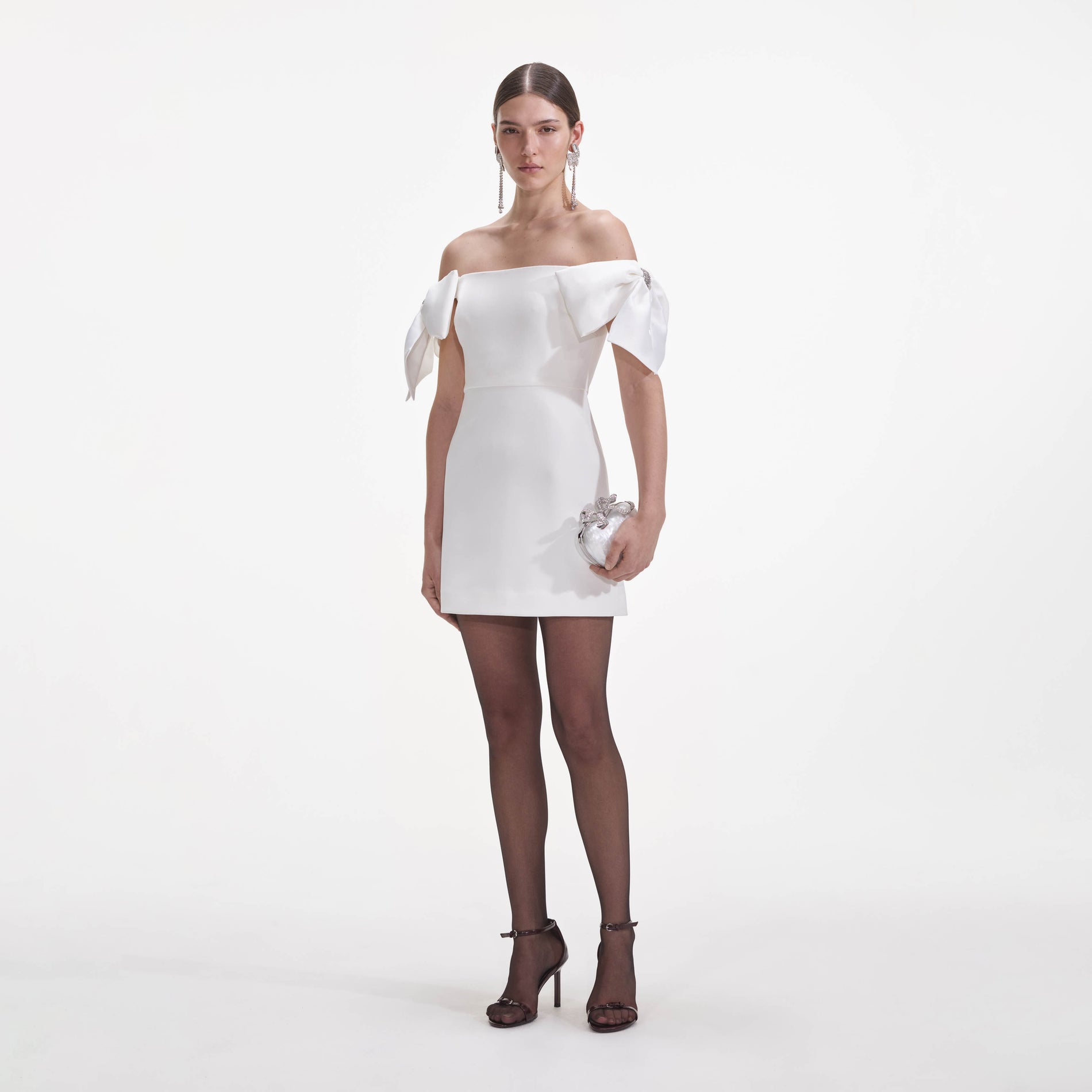 Side view of a woman wearing the White Crepe Bow Mini Dress