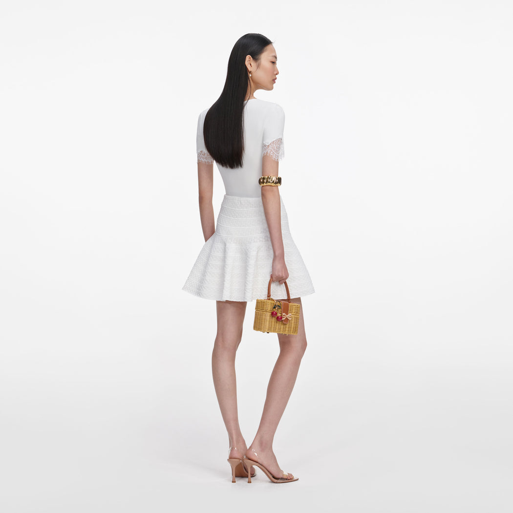 Side view of a woman wearing the White Pointelle Knit Mini Skirt