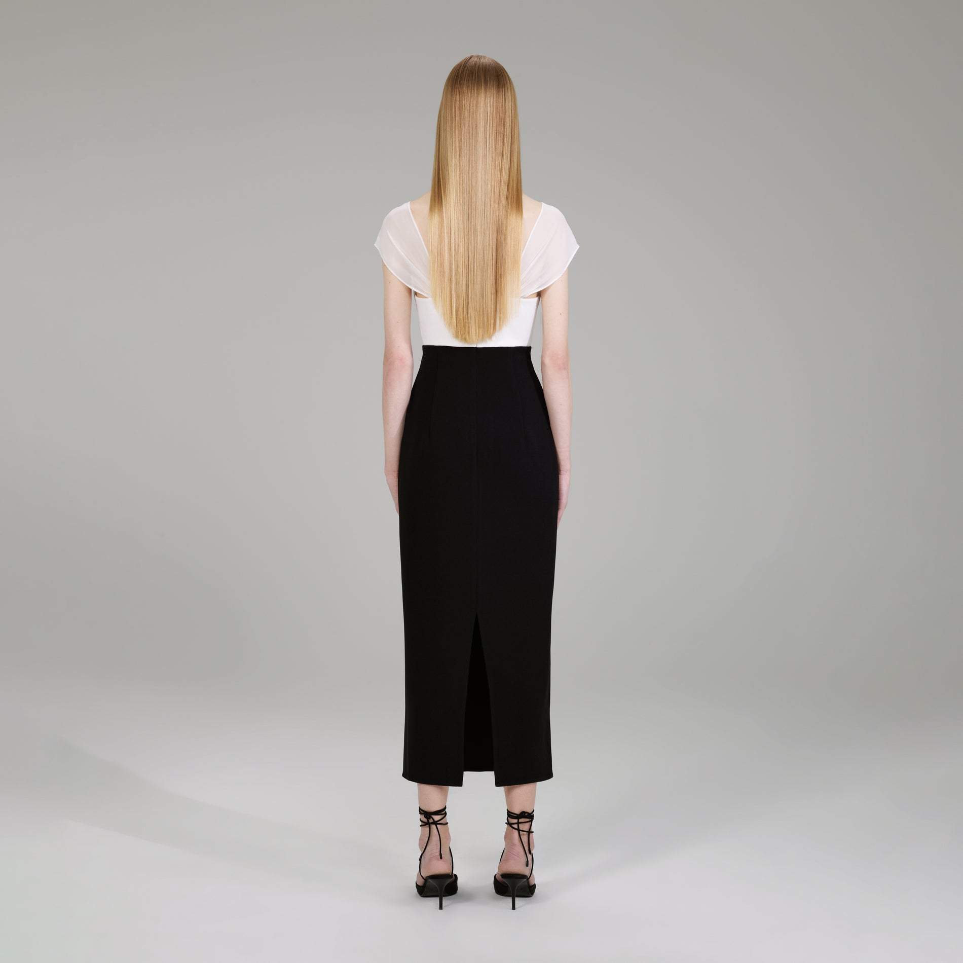 A woman wearing the Black And White Crepe Bow Midi Dress