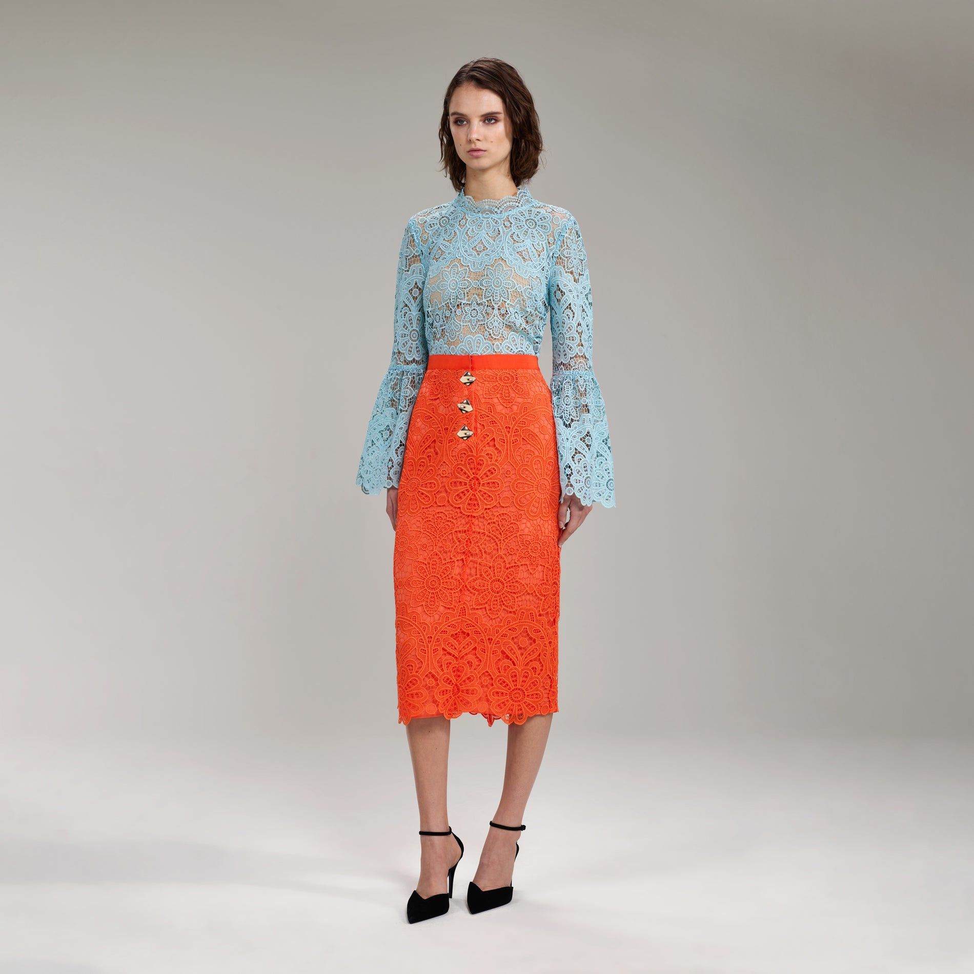 A woman wearing the Light Blue Floral Guipure Angel Sleeve Blouse