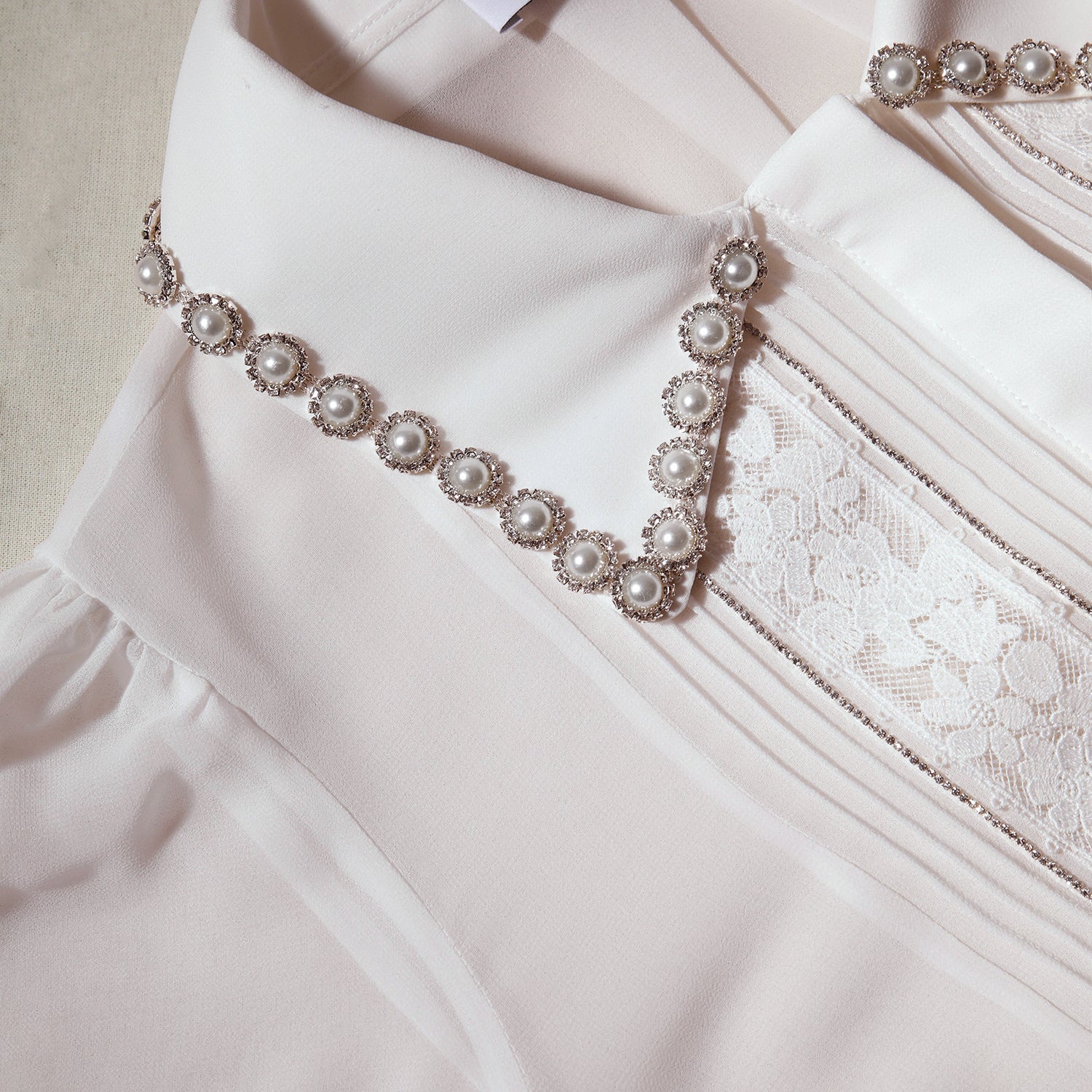 A close up of the fabric for the White Chiffon Rhinestone Detail Top
