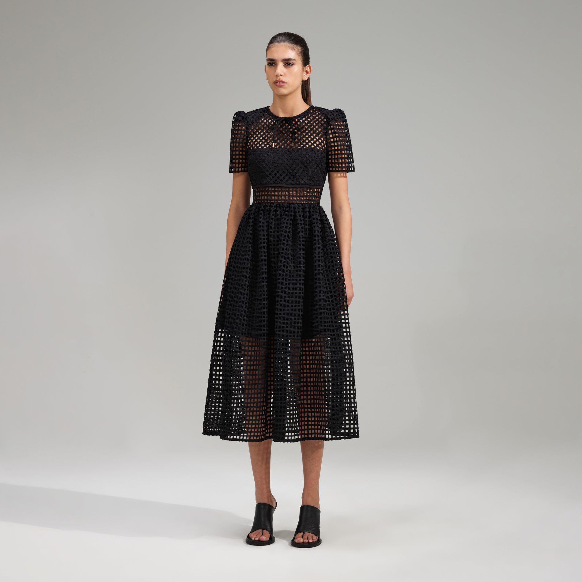 A woman wearing the Black Grid Lace Midi Dress
