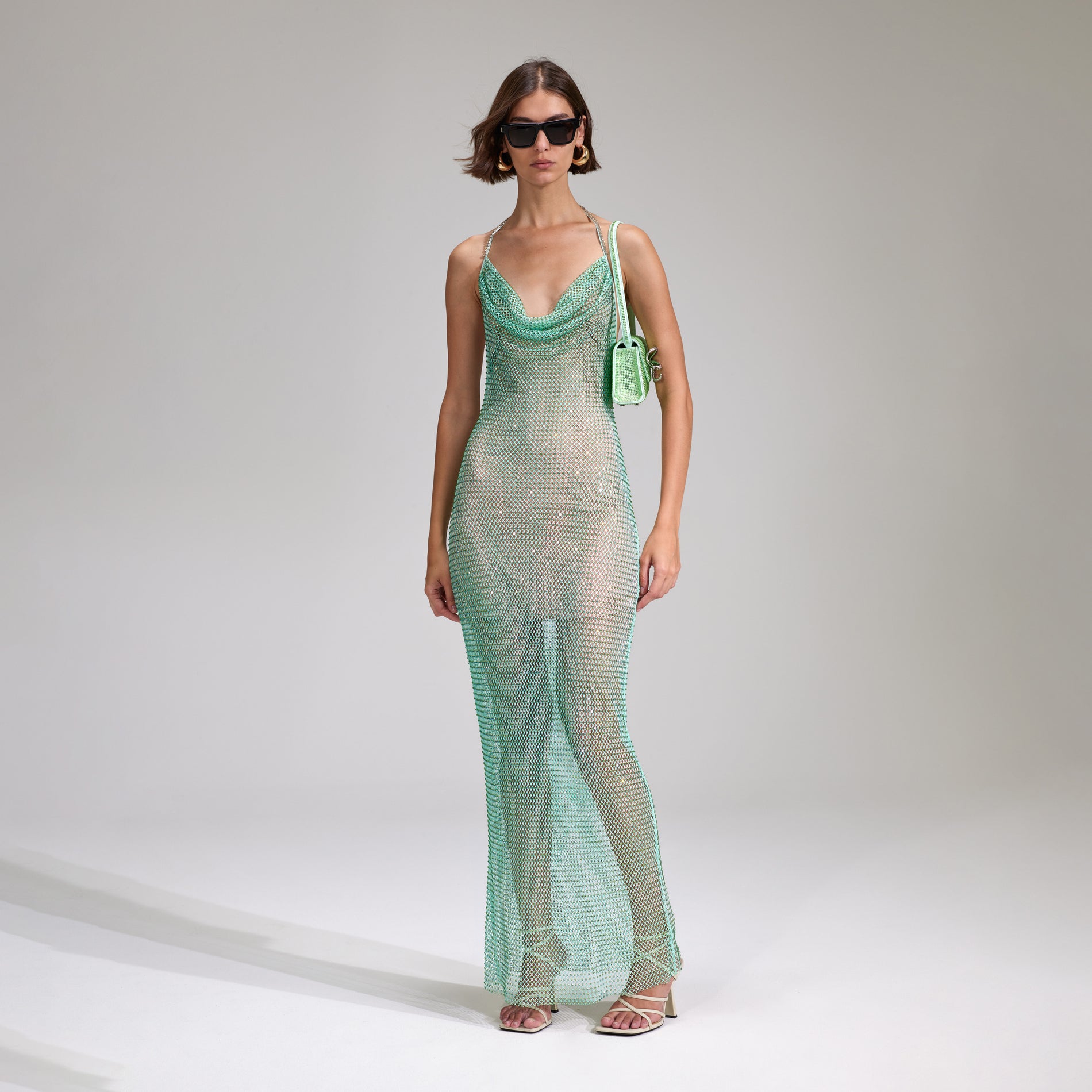 A woman wearing the Mint Rhinestone Fishnet Cowl Maxi Dress