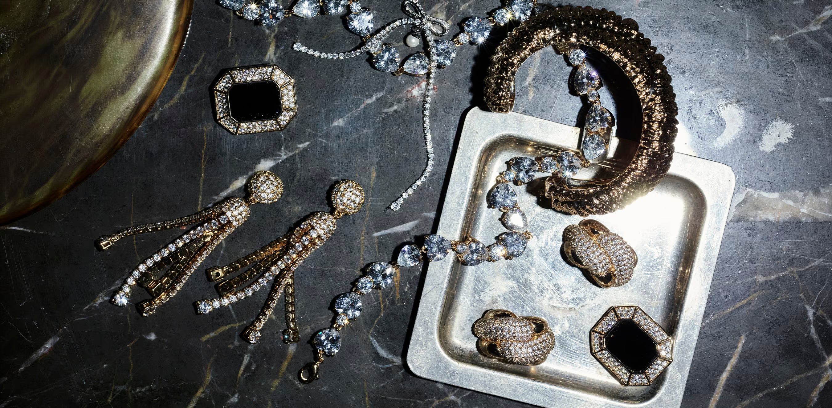 Collection of jewellery including earrings and a bracelet on a dark marble surface.
