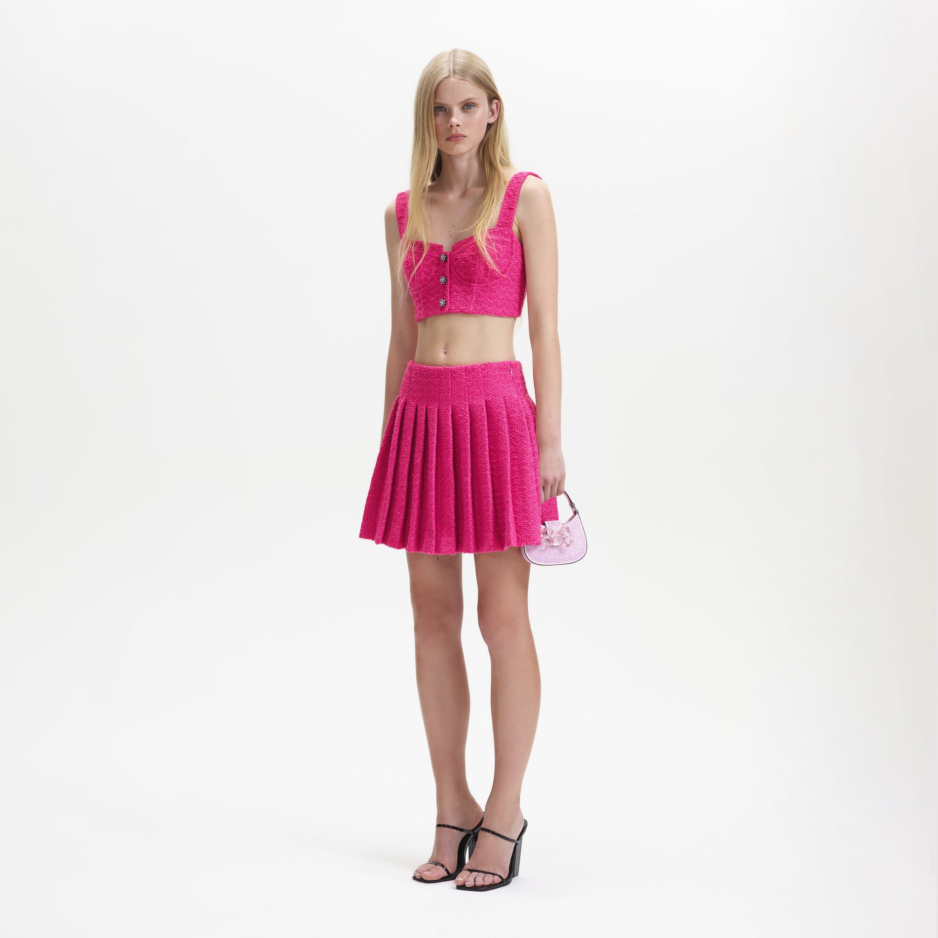 A woman wearing the Fuchsia Boucle Pleated Mini Skirt