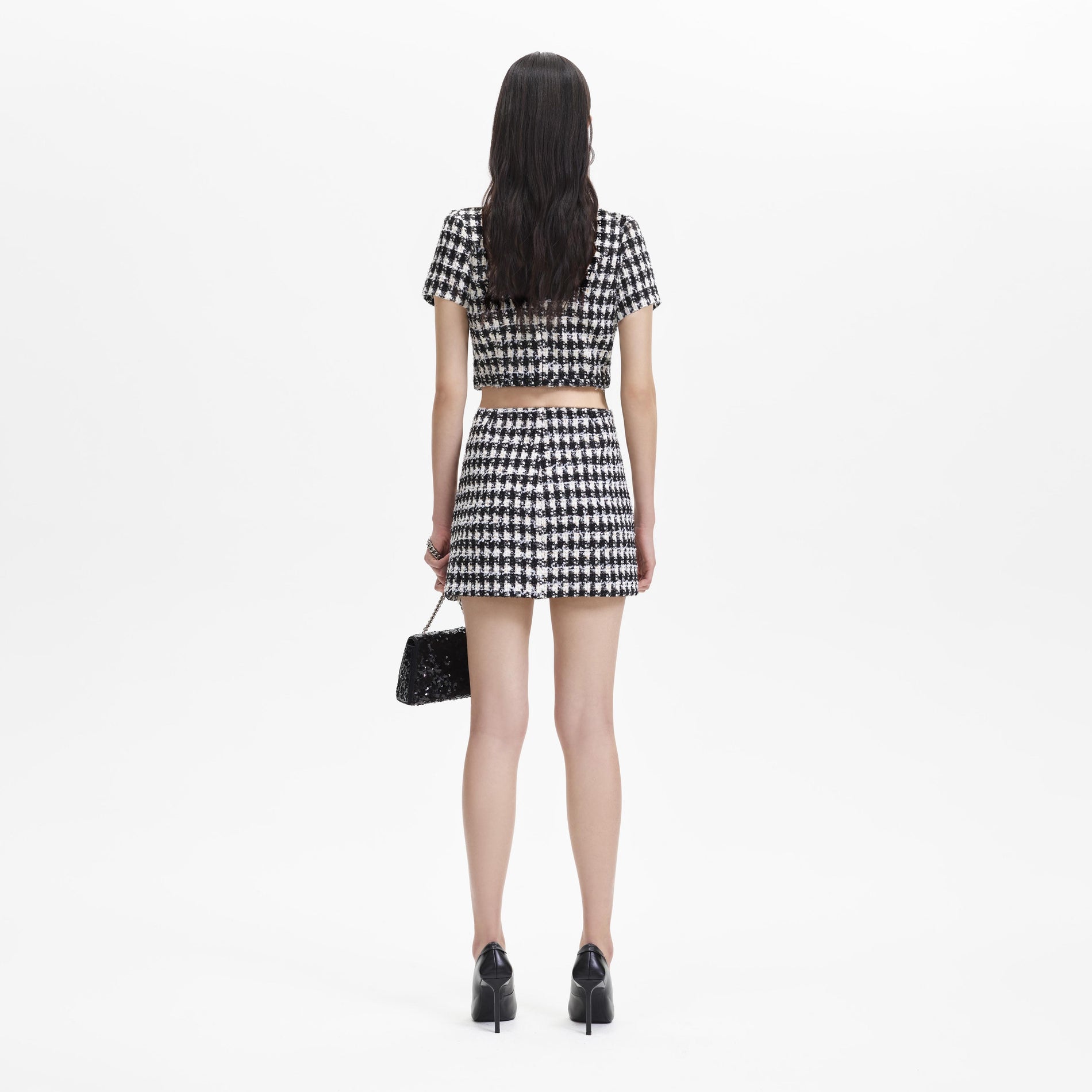 Back view of a woman wearing the Black Check Boucle Mini Skirt