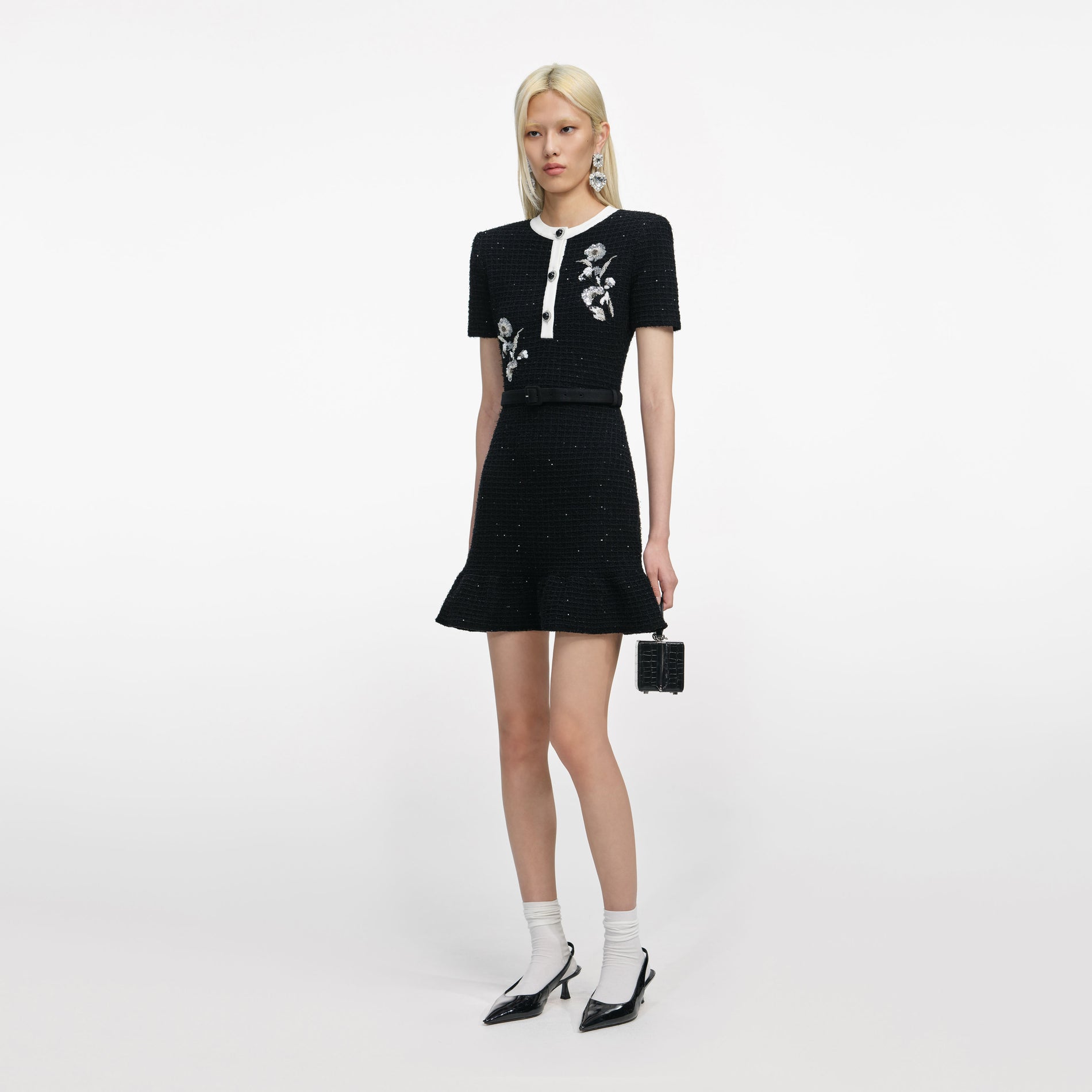 Side view of a woman wearing the Black Floral Textured Knit Mini Dress