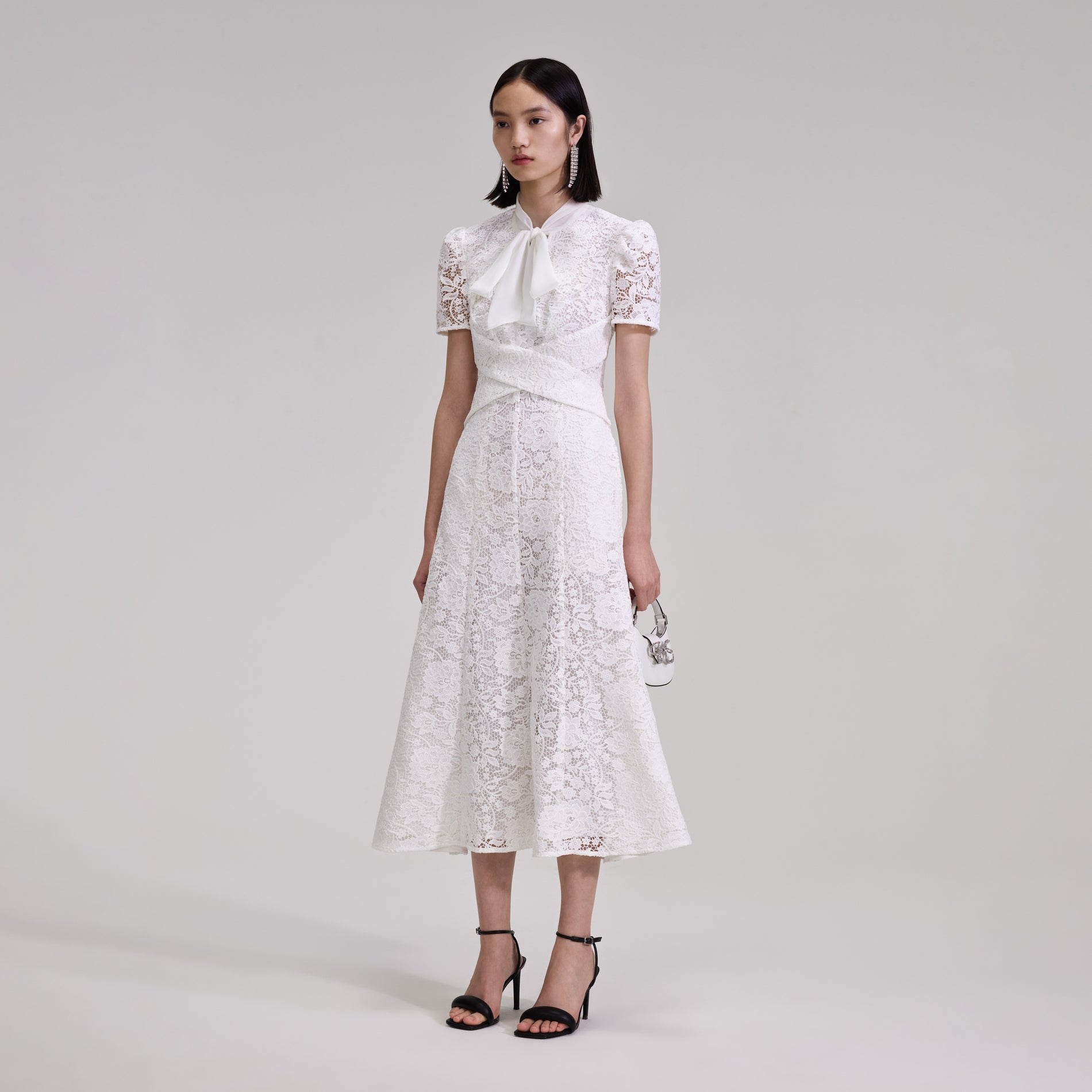A woman wearing the White Cord Lace Crossover Midi Dress
