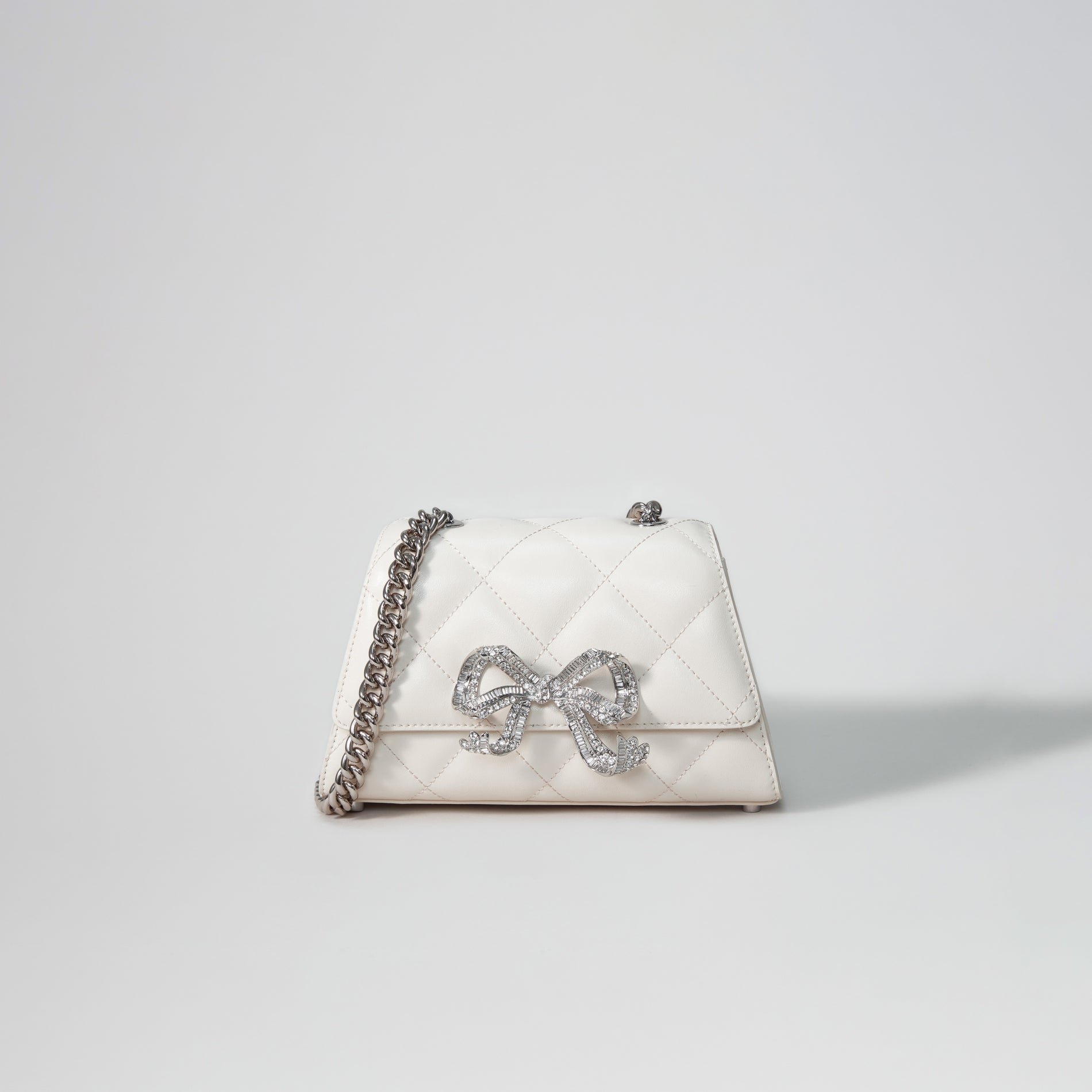 A woman wearing the Cream Quilted Shoulder Mini Bow Bag