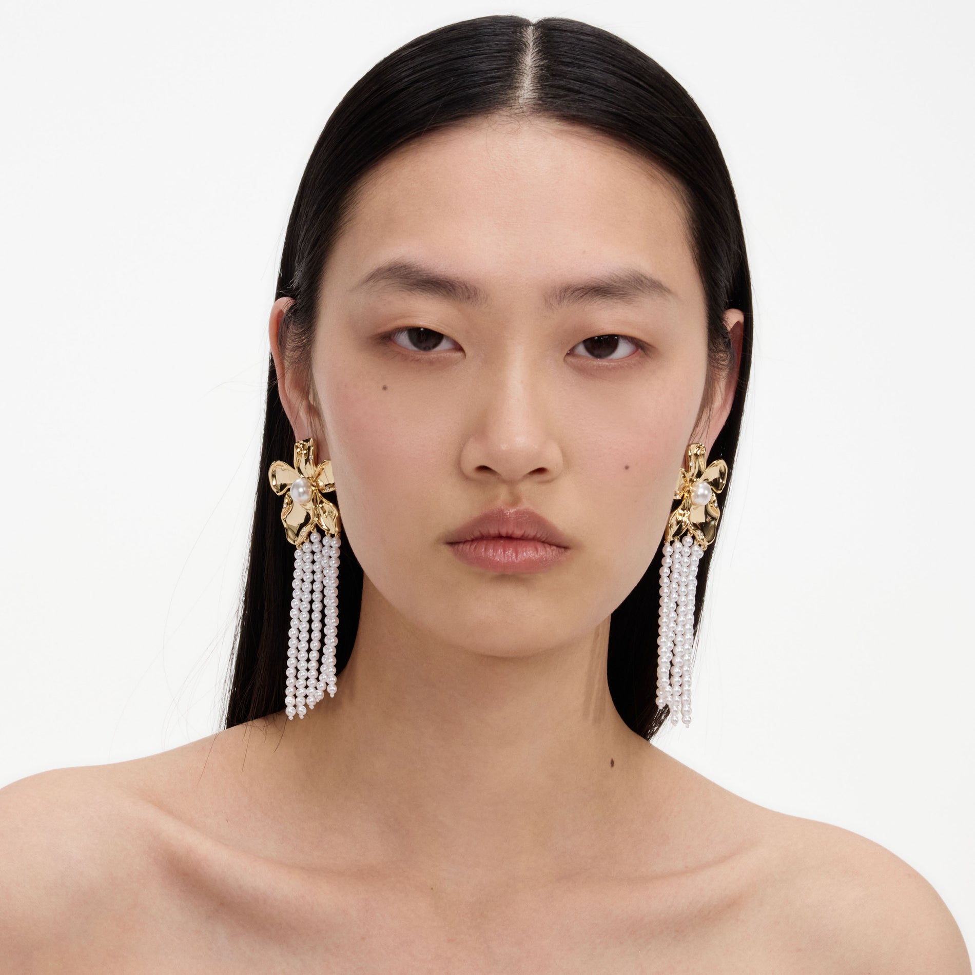 A close up of a woman wearing the Gold Flower Pearl Dangle Earrings