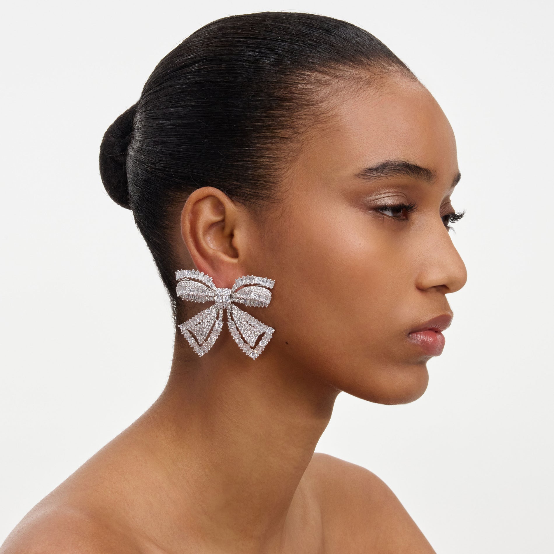 A close up of a woman wearing the Crystal Bow Earrings