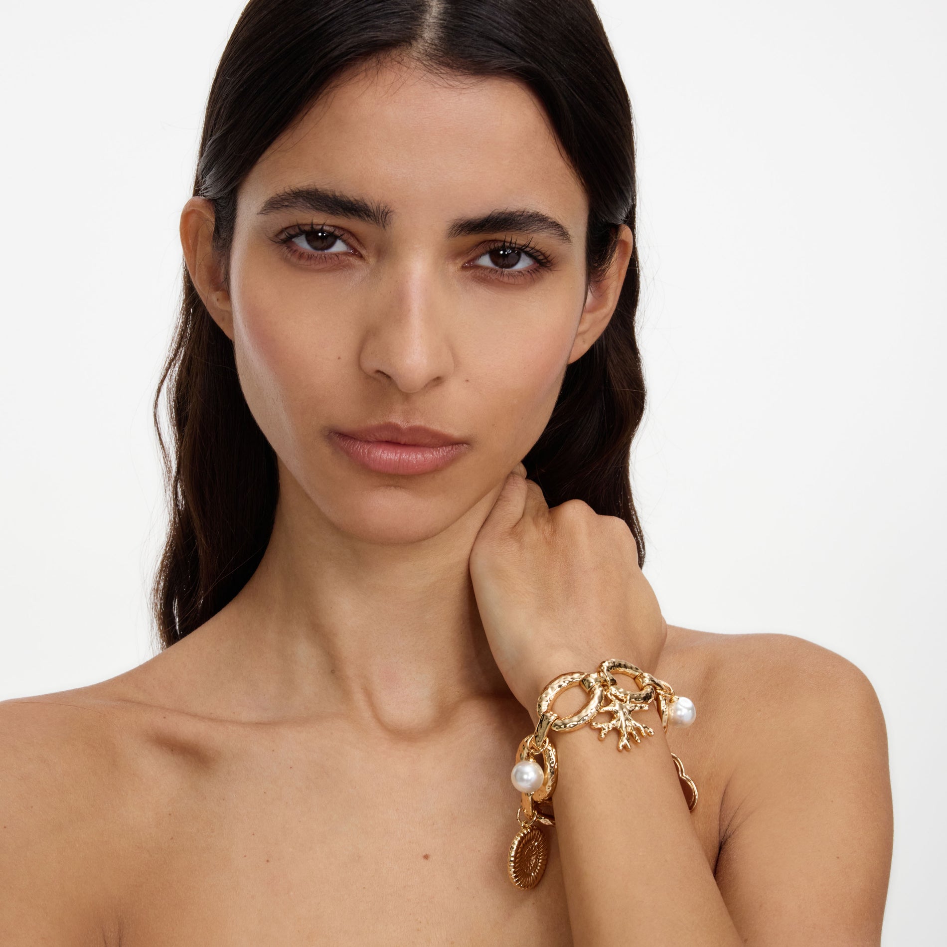 A close up of a woman wearing the Gold Coral Charm Bracelet