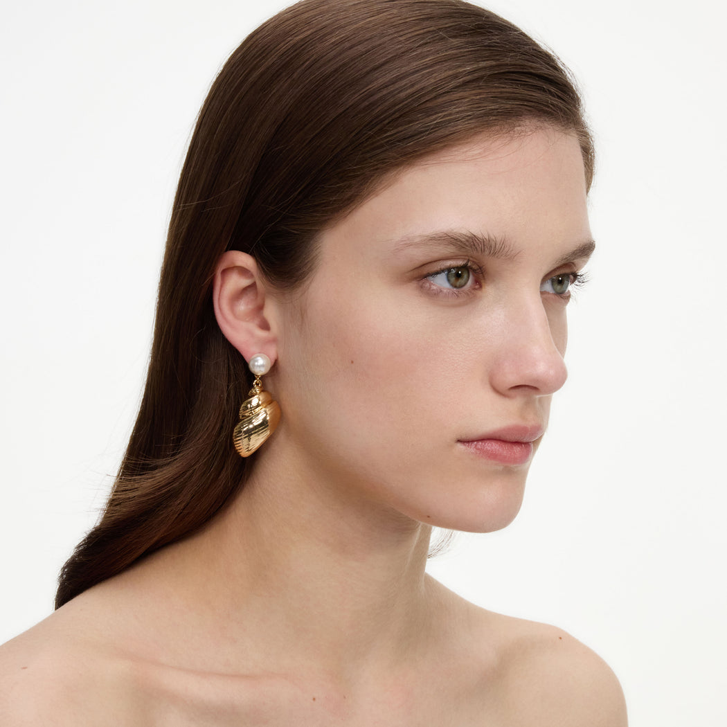 A close up of a woman wearing the Pearl Gold Shell Earrings