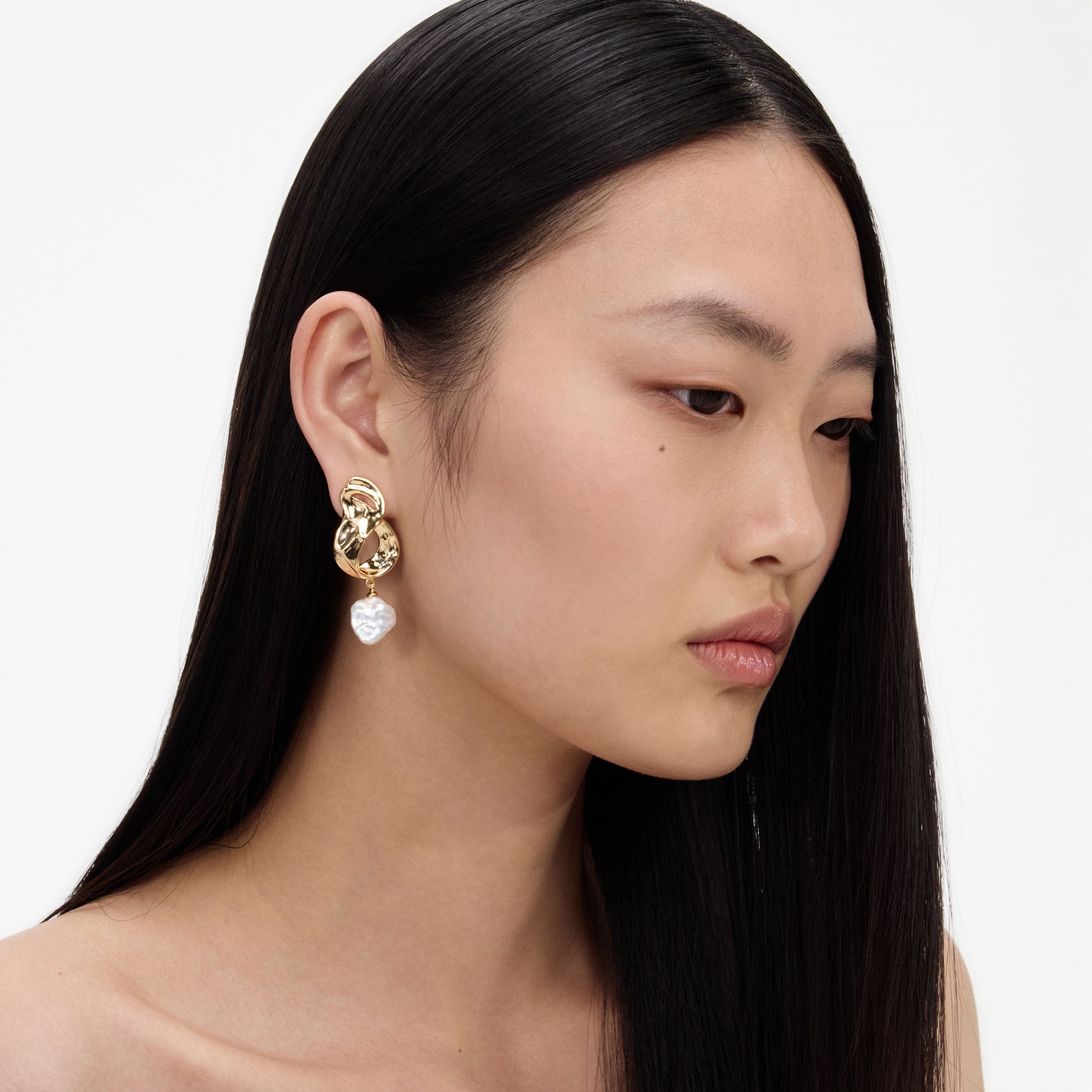 A close up of a woman wearing the Gold Link Pearl Drop Earrings