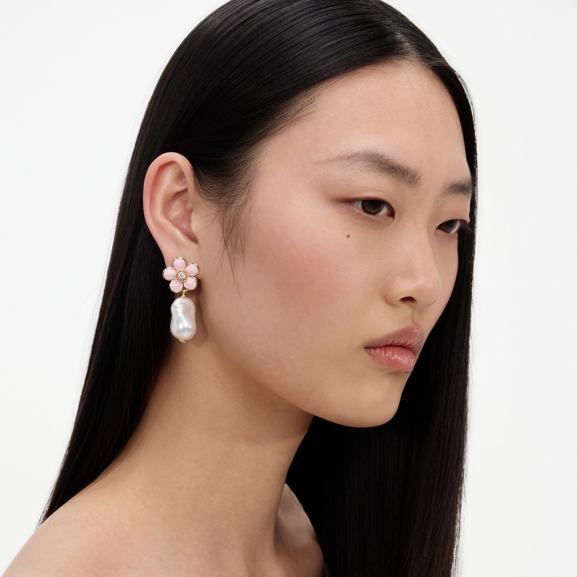 A close up of a woman wearing the Pink Flower Pearl Drop Earrings