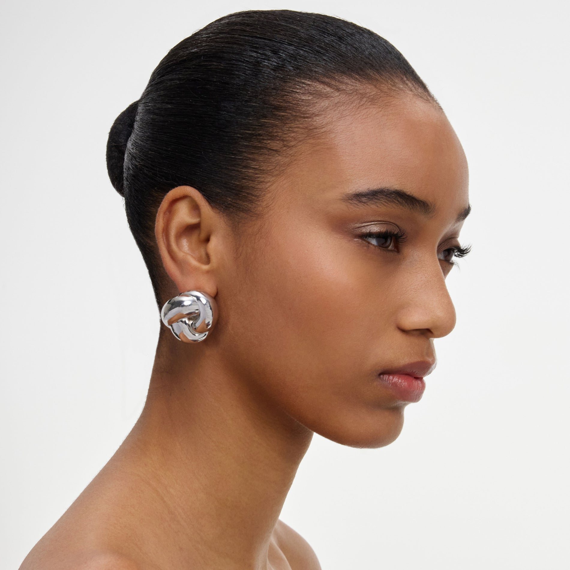 A close up of a woman wearing the Silver Knot Earrings