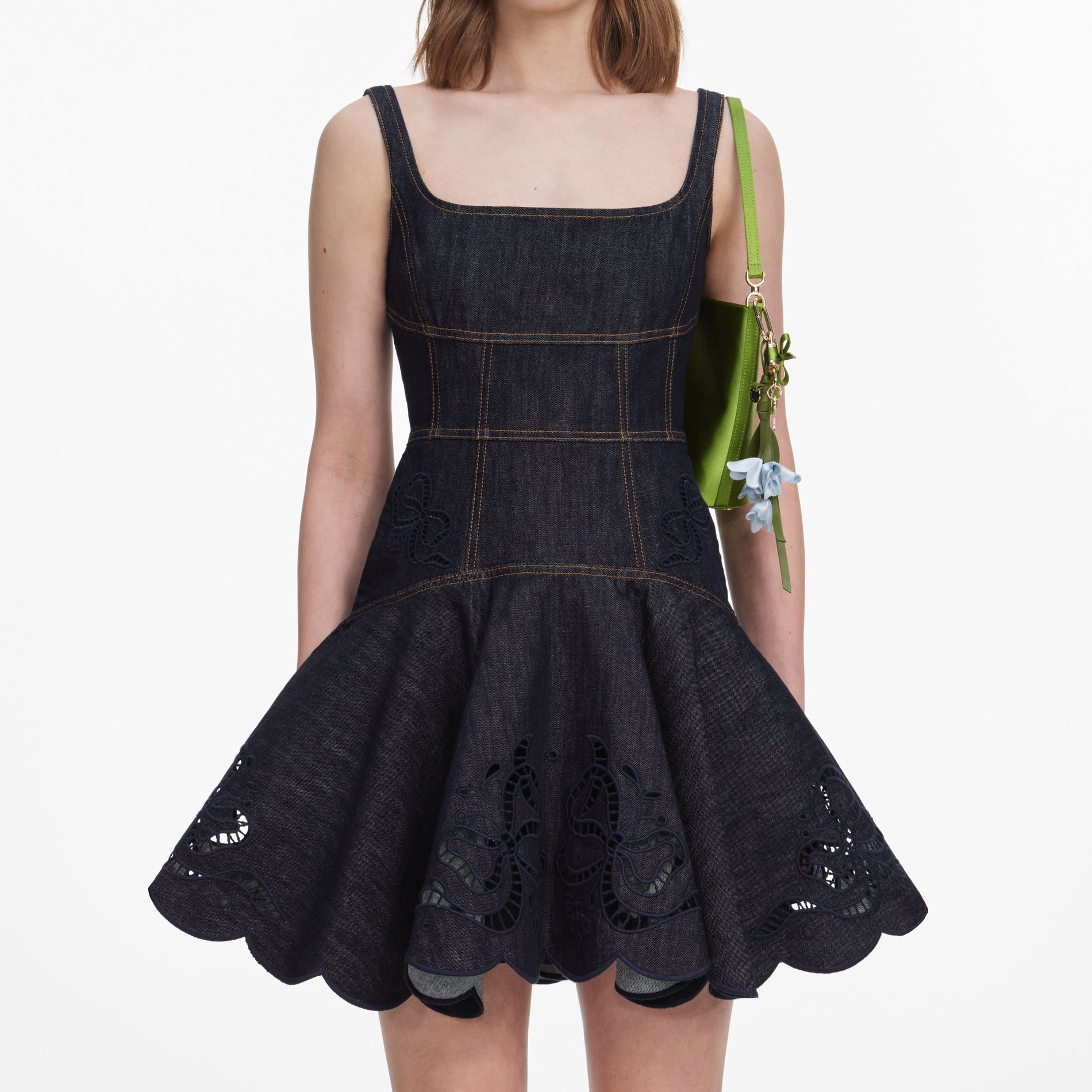 A close up of a woman wearing the Indigo Denim Bow Embroidered Mini Dress