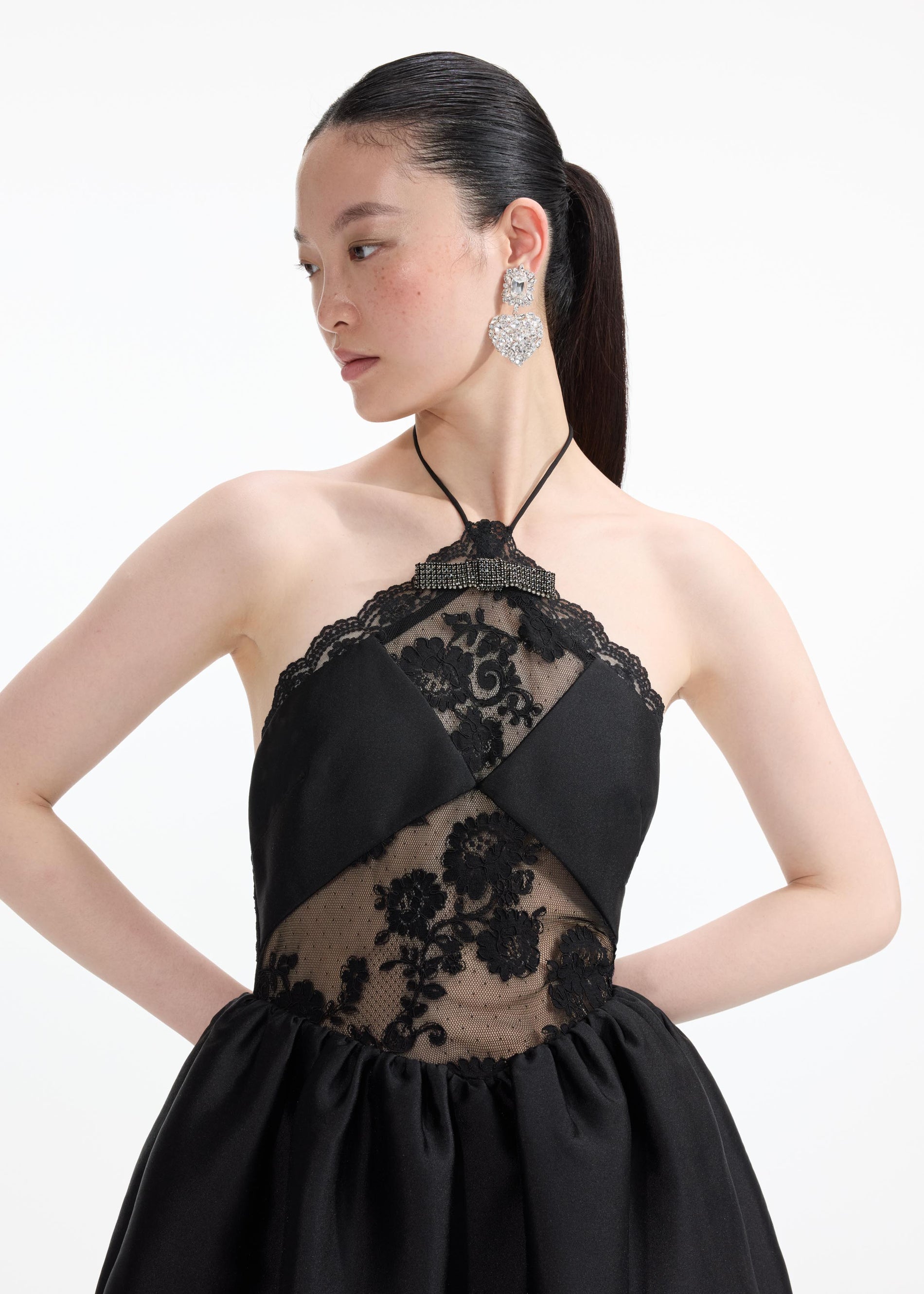 A close up of a woman wearing the Crystal Heart Tiered Earrings