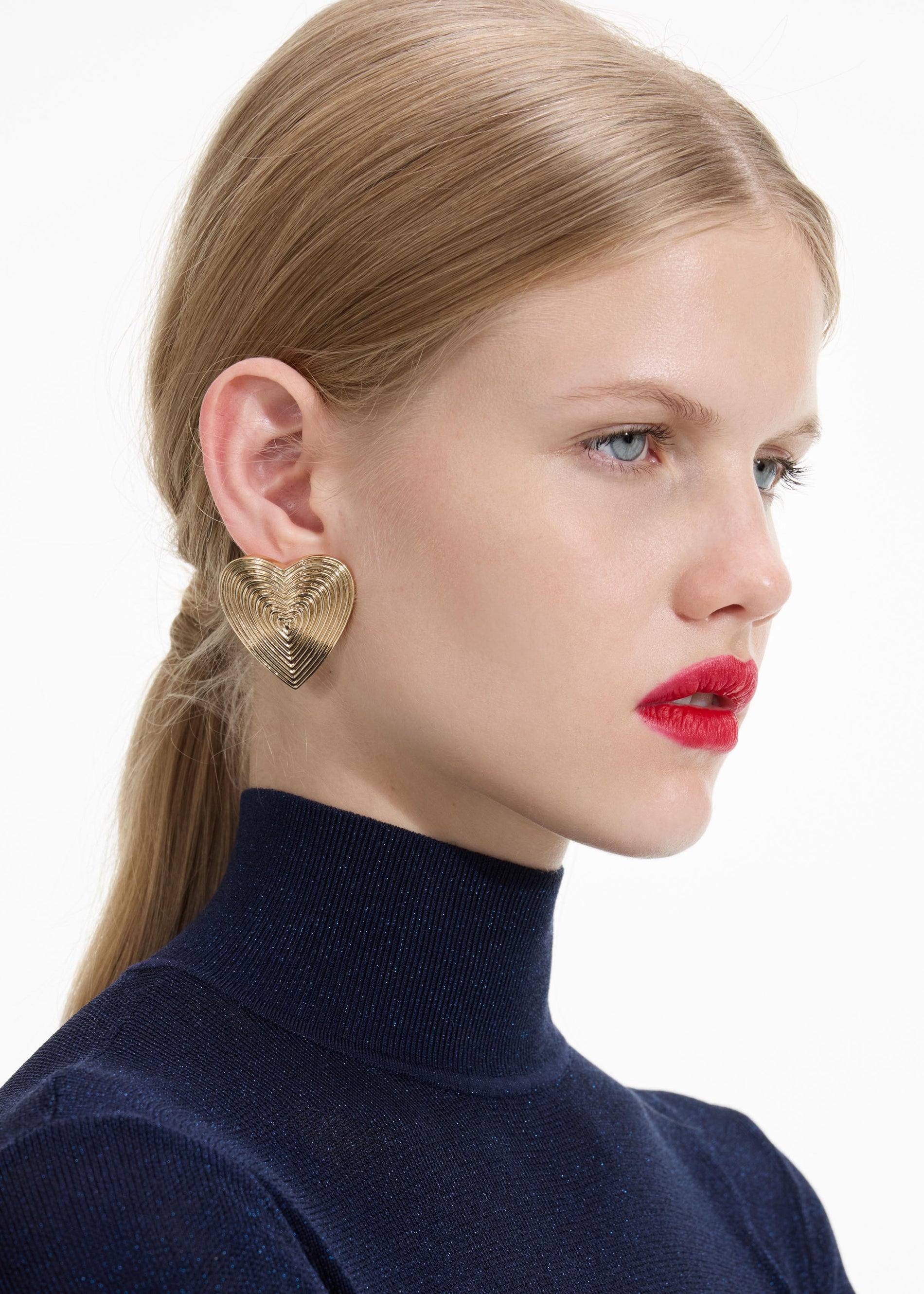 Back view of a woman wearing the Gold Heart Ridged Earrings