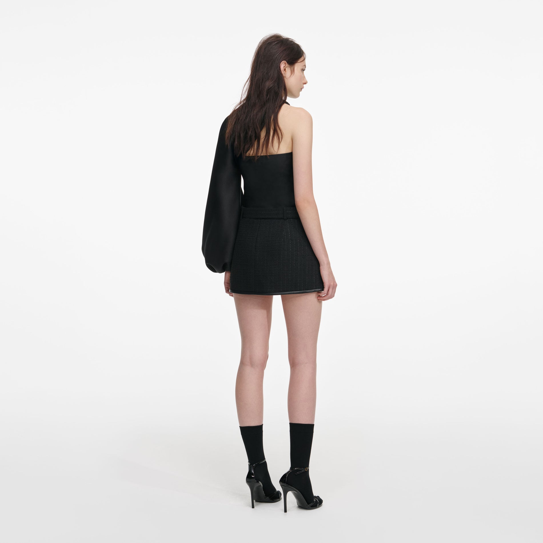 Back view of a woman wearing the Black Boucle Mini Skirt