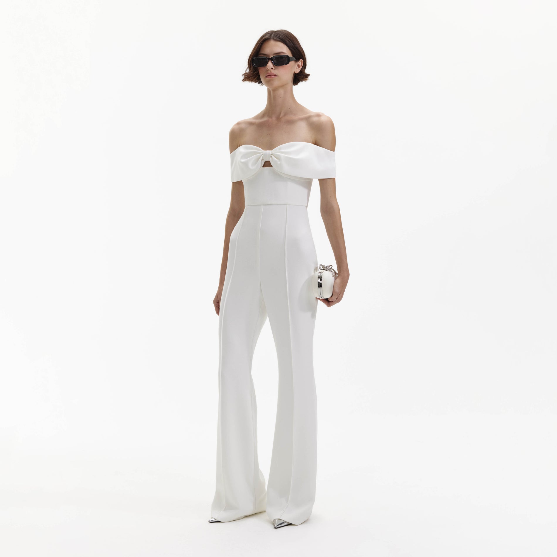 Side view of a woman wearing the White Crepe Bow Jumpsuit
