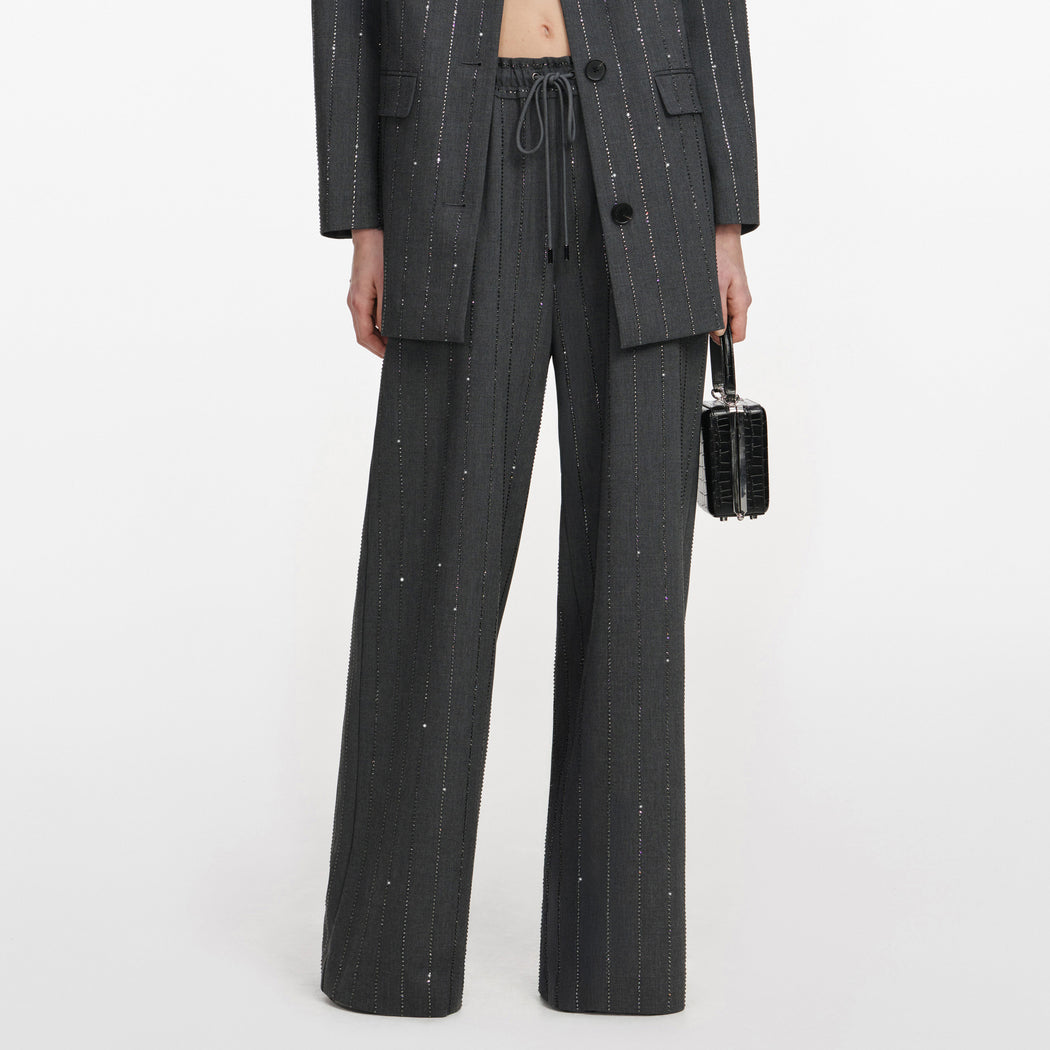 A close up of a woman wearing the Grey Rhinestone Pinstripe Trousers