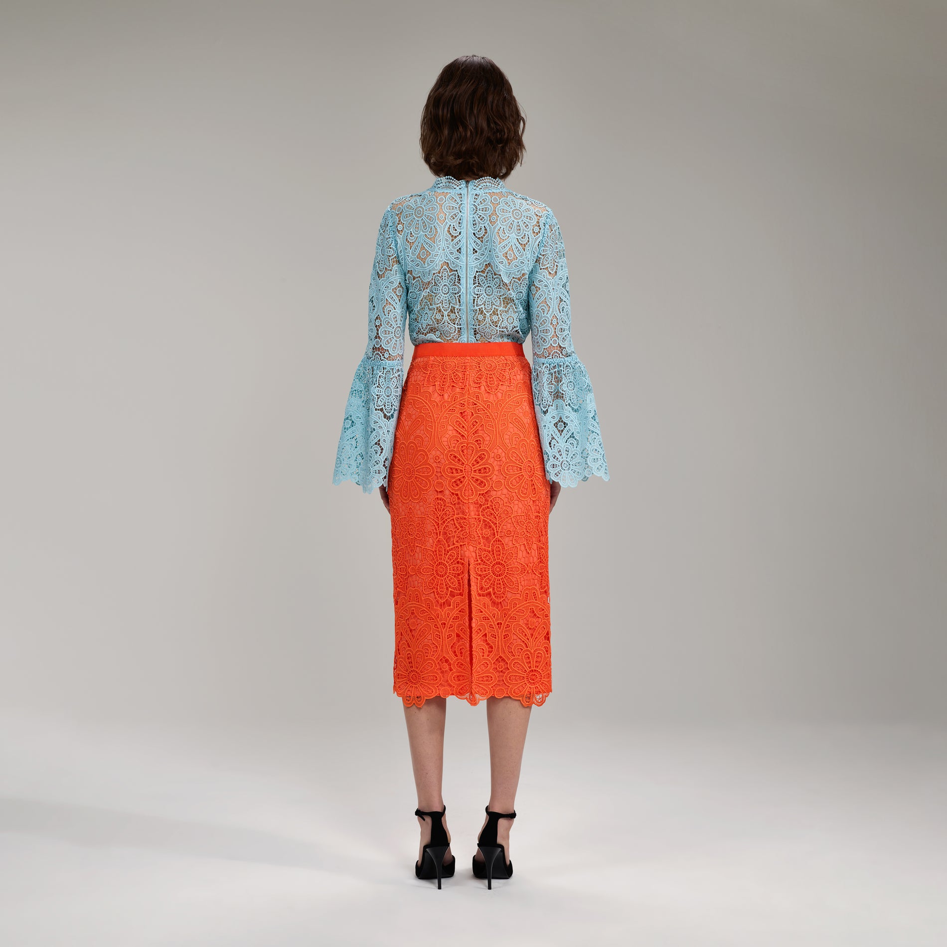 A woman wearing the Light Blue Floral Guipure Angel Sleeve Blouse