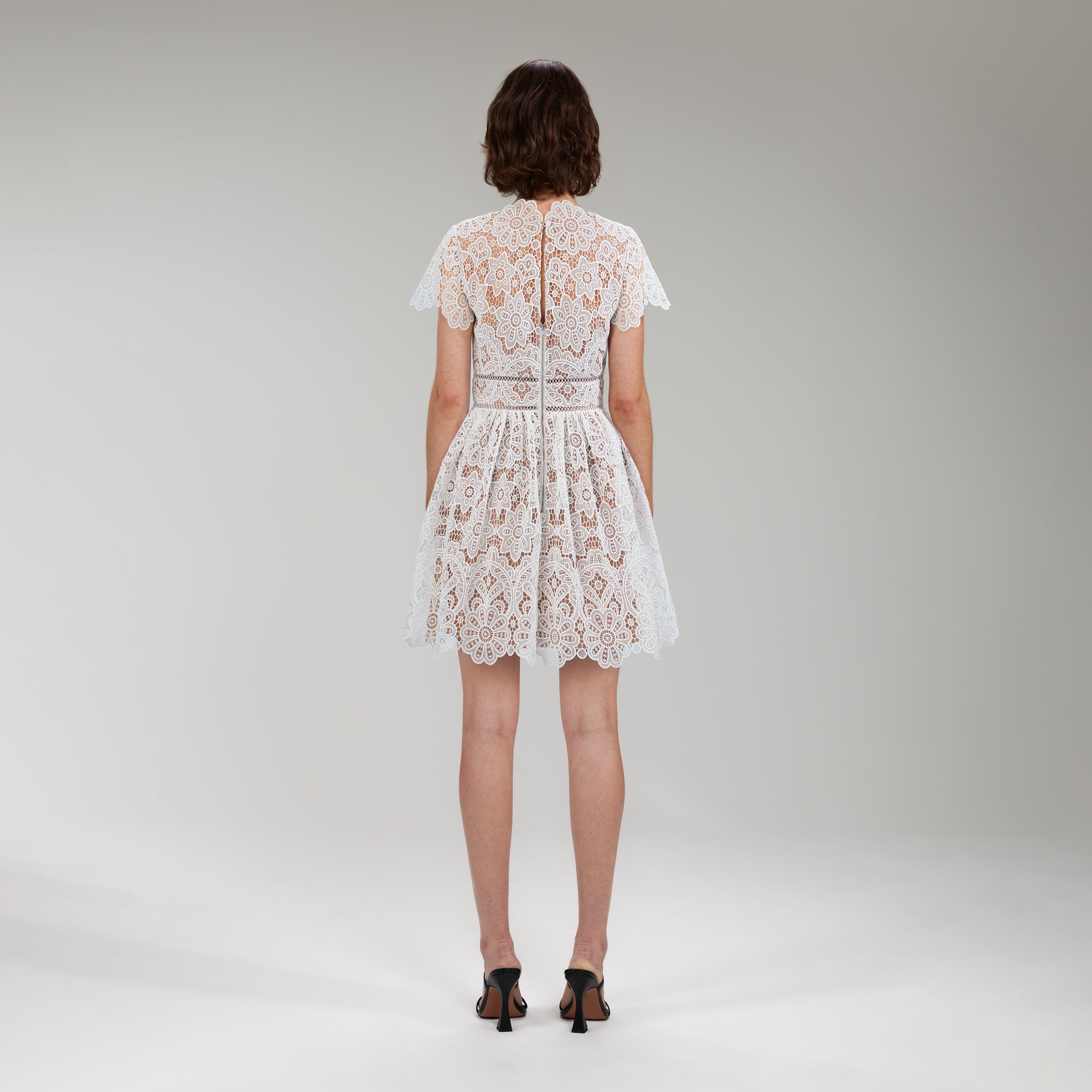 A woman wearing the White Floral Guipure Lace Mini Dress