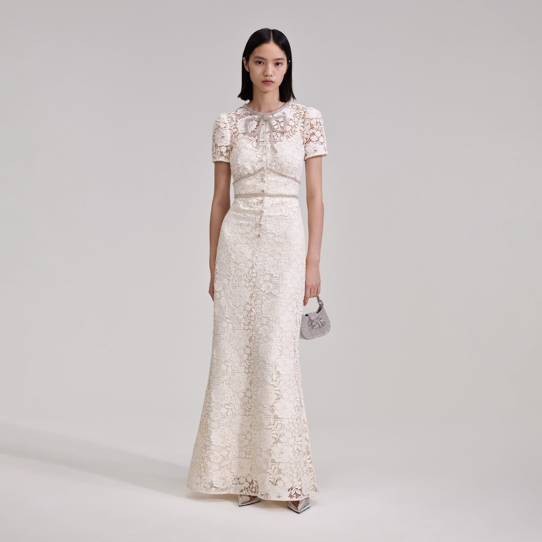 A woman wearing the Cream Cord Lace Bow Maxi Dress