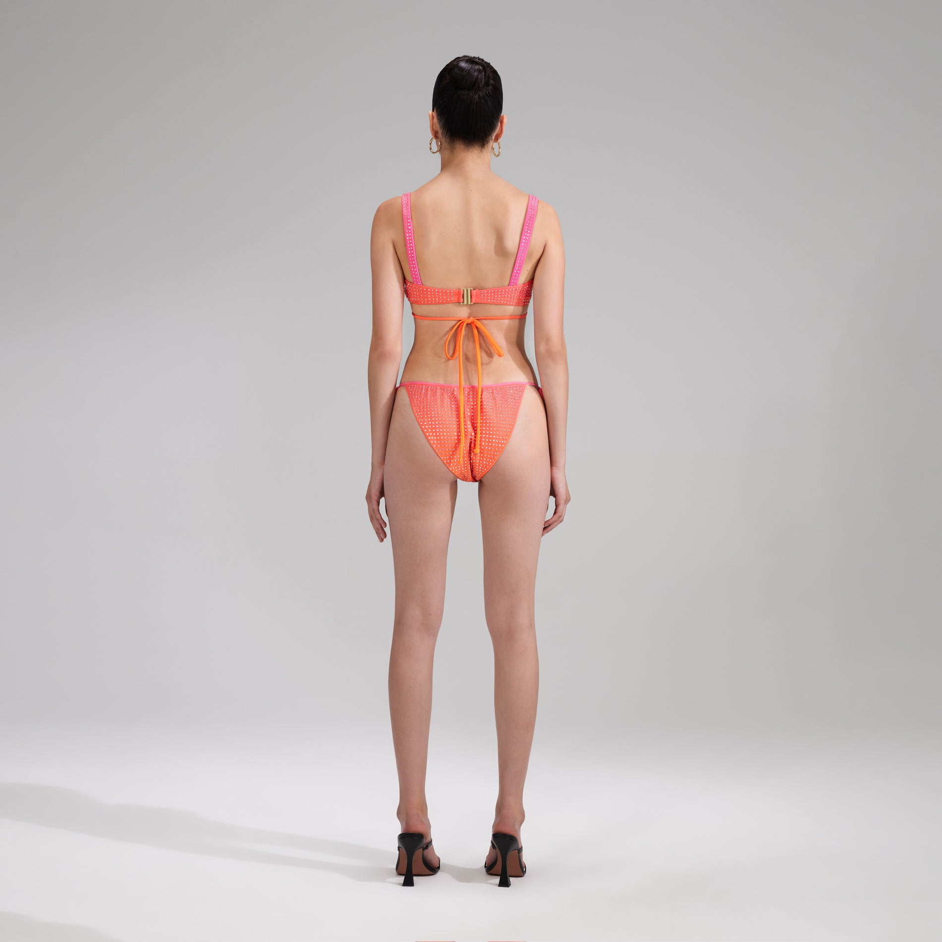A woman wearing the Orange Rhinestone Tie Side Bikini Brief